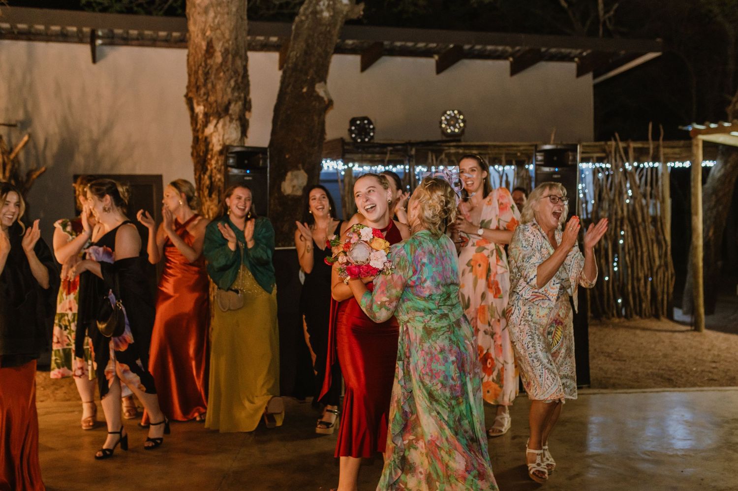Guests enjoying themselves on a dance floor at an outdoor wedding venue with ambient lighting.