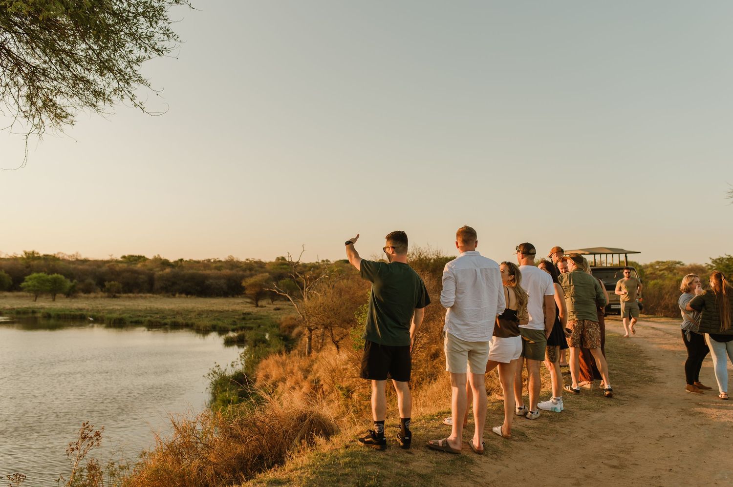 People standing along a waterfront viewing area during sunset.