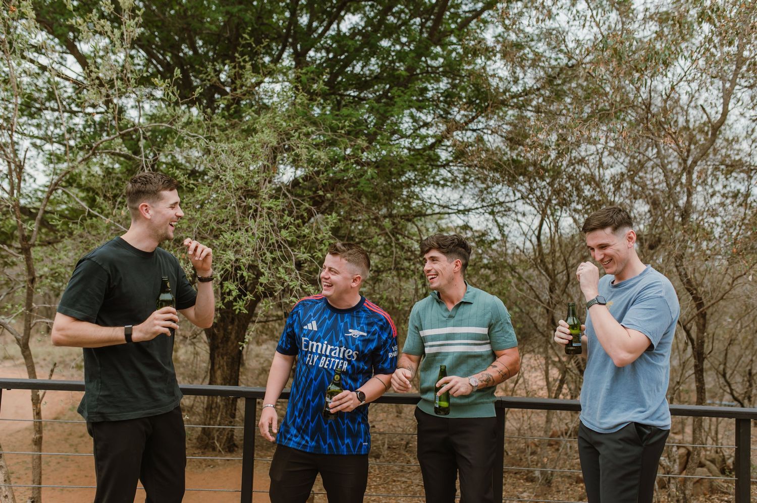 A group poses casually outdoors against a backdrop of trees and natural landscape.