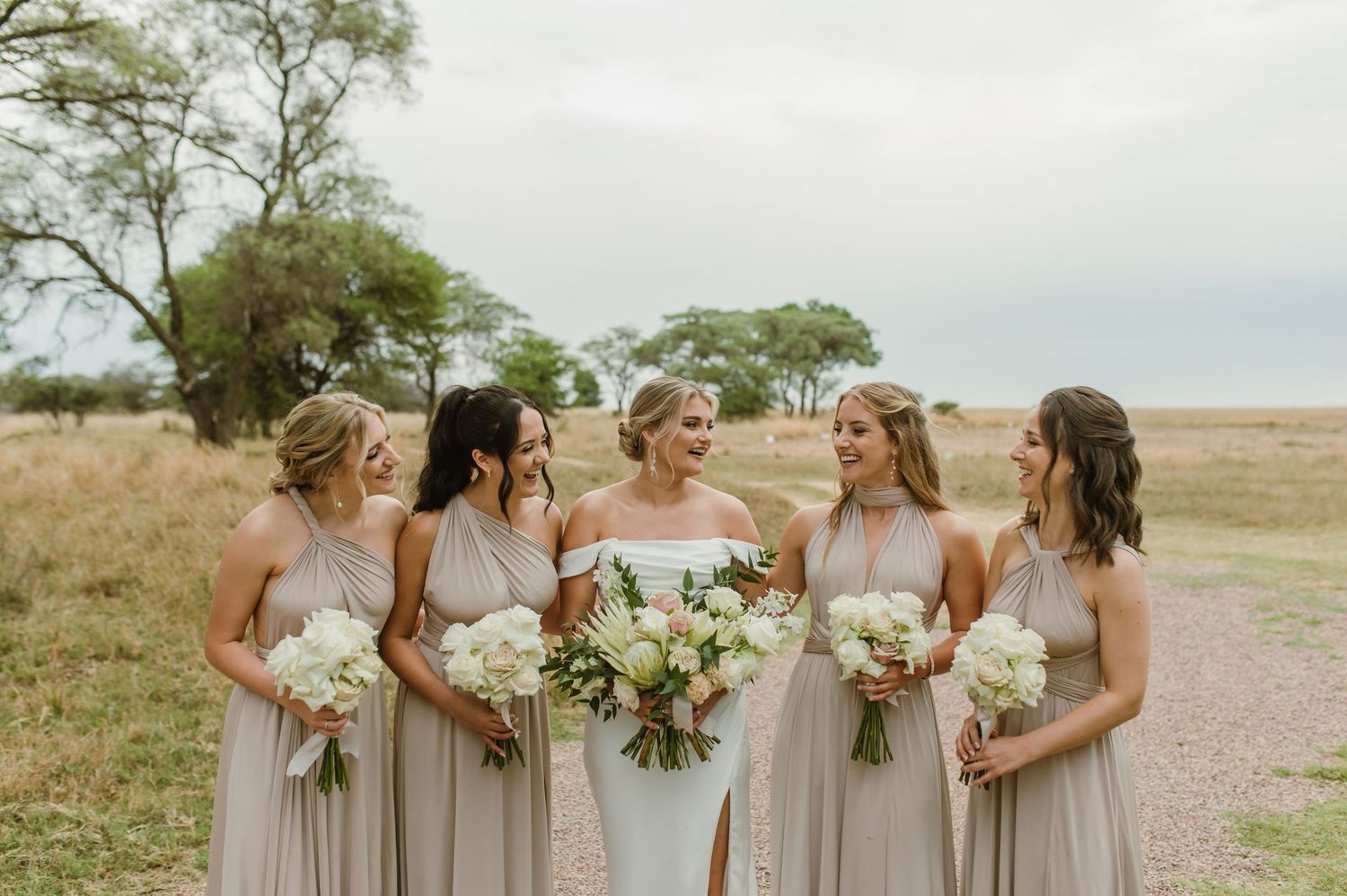 Bridal party holding bouquets while walking together in a scenic outdoor setting.
