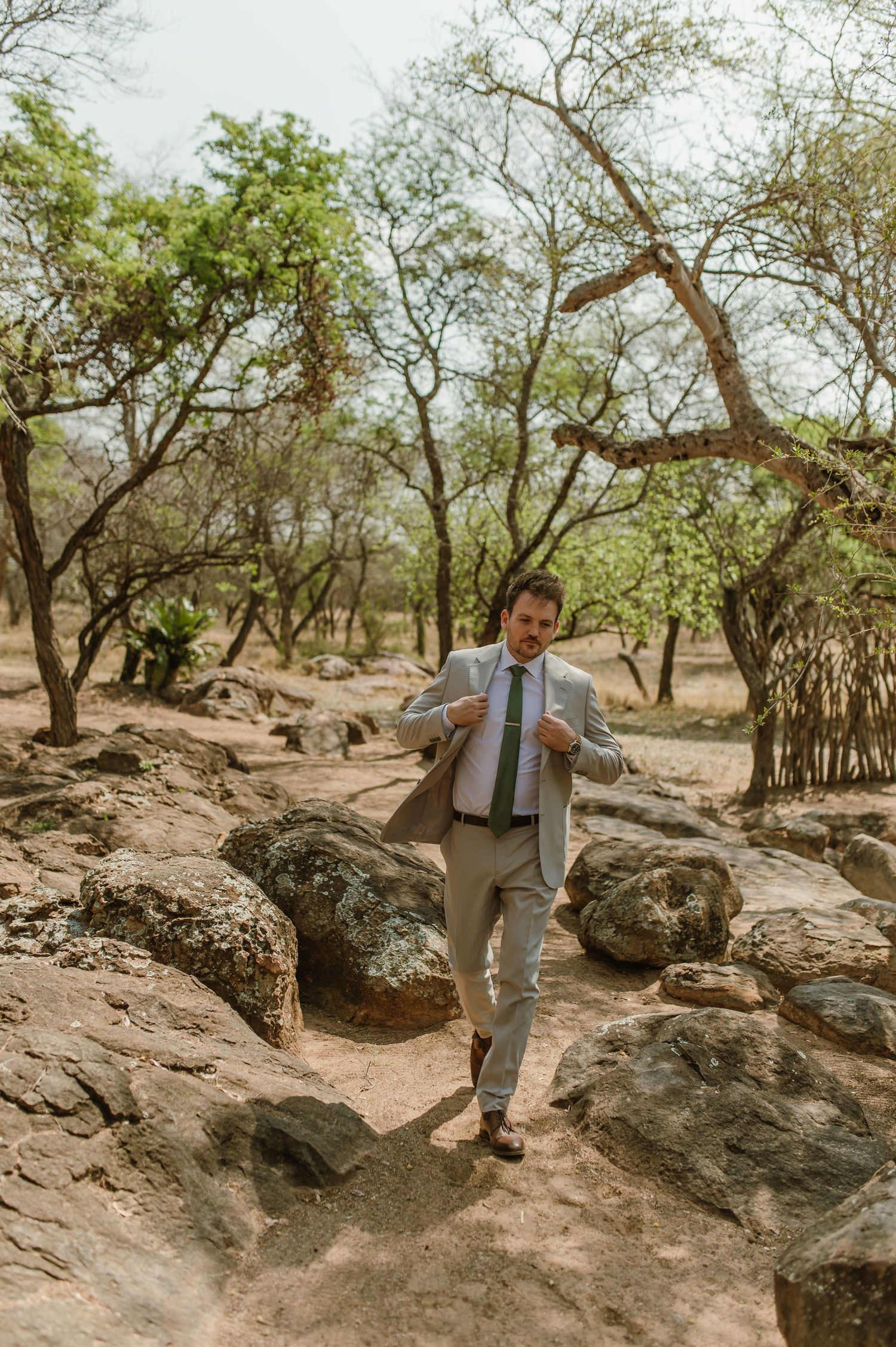 Person in grey suit navigating rocky terrain in a desert landscape.
