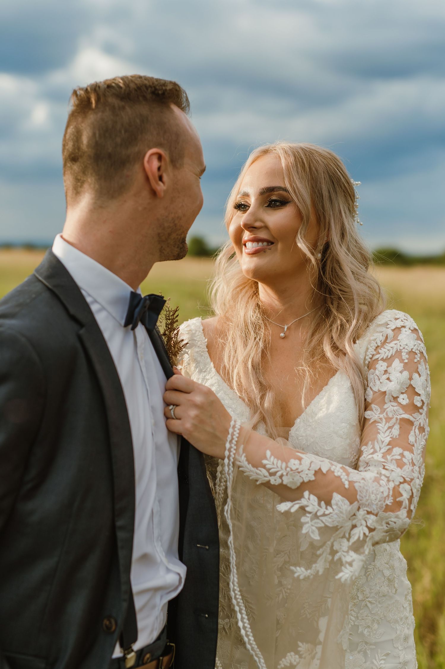Intimate wedding portraits captured in a golden field under cloudy skies.