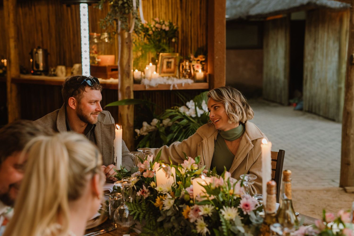 Wedding reception venue with wooden interior and elegant floral arrangements on dining tables.