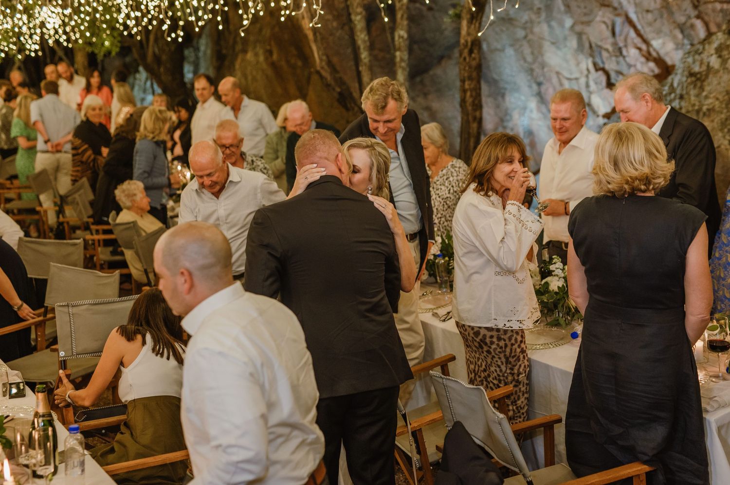 Wedding reception guests mingling at tables under magical string light decor.