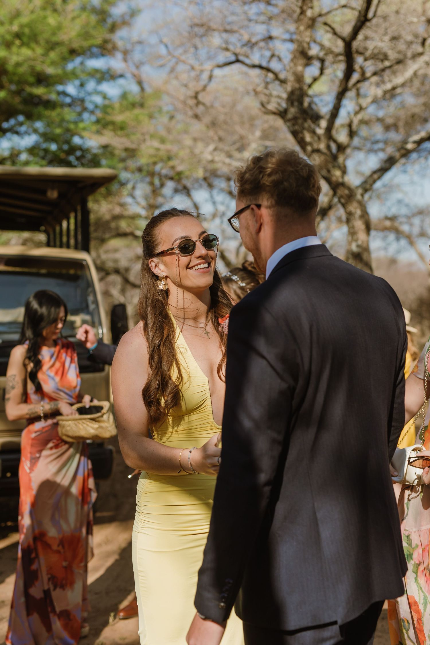 Wedding guests in yellow and black attire share a joyful moment during an outdoor celebration.