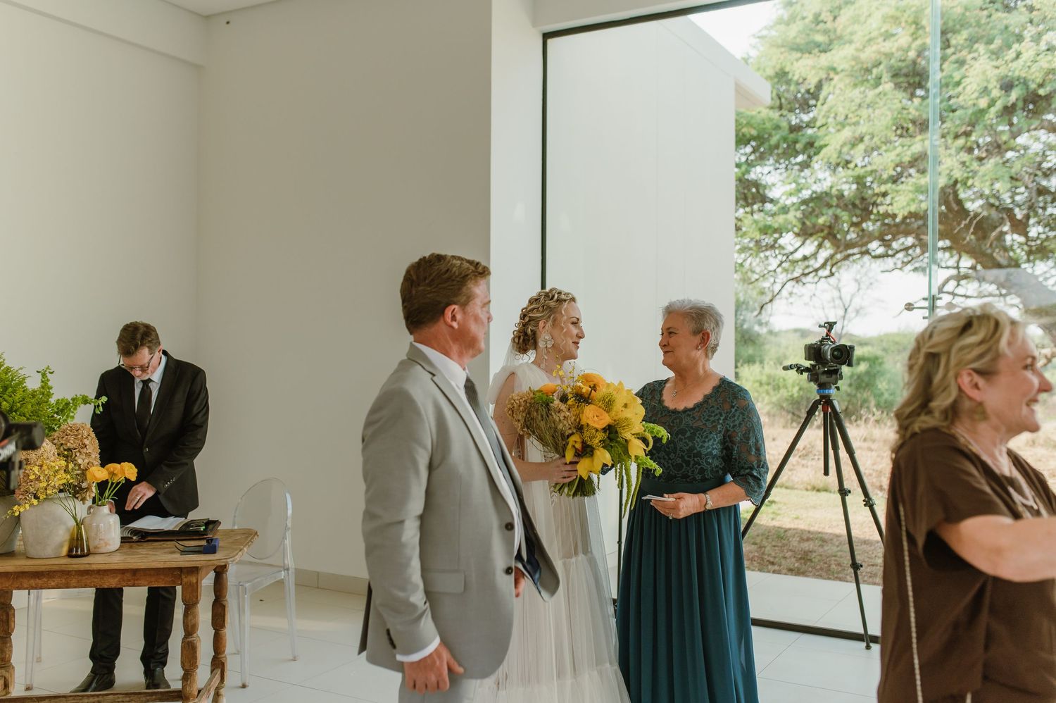 Modern wedding venue interior with large windows and guests gathering before the ceremony.