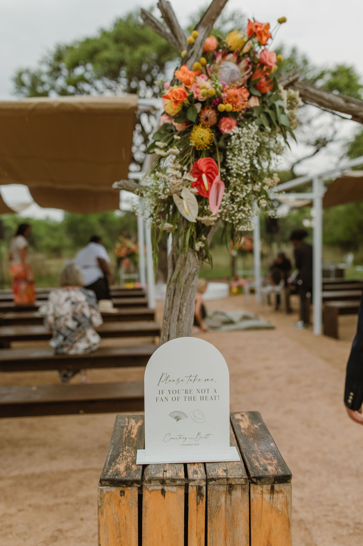 Floral arrangements in glass vases with orange and white flowers displayed on wooden crates.