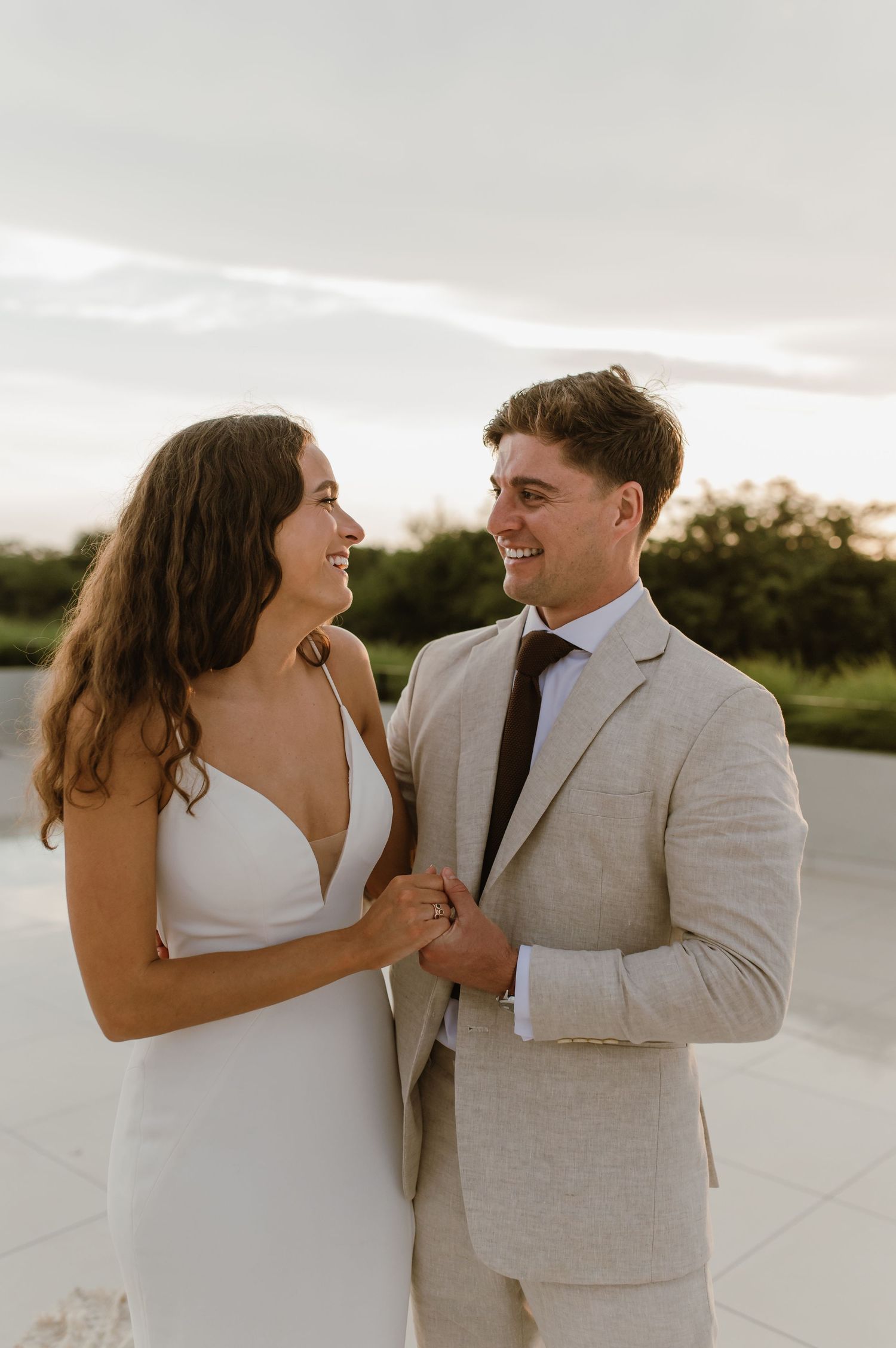 A couple in wedding attire shares a candid laughing moment on an outdoor terrace.