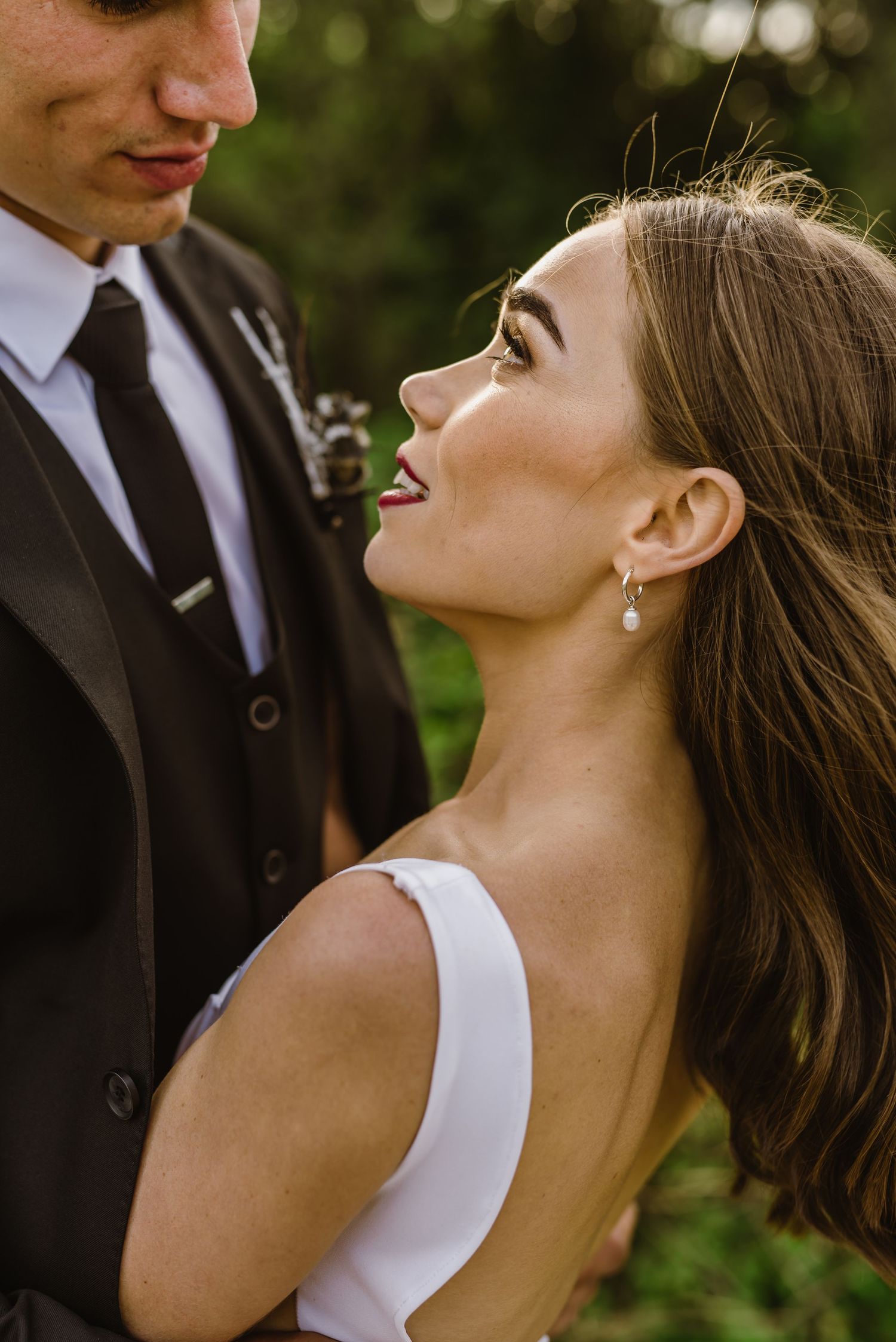 A romantic moment captured between newlyweds against a natural green backdrop.