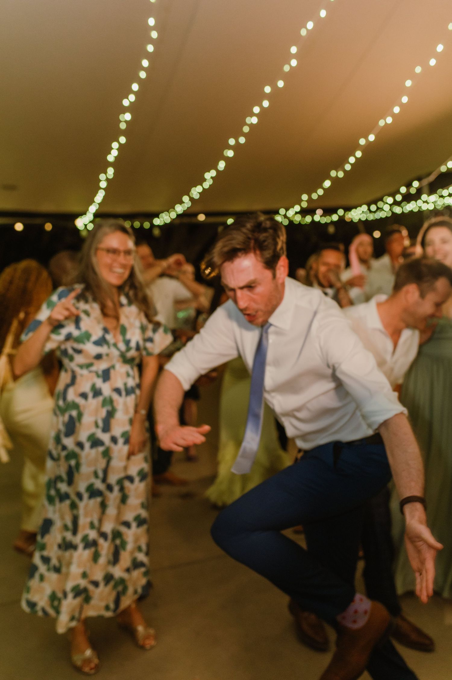 Energetic dance moves captured at a wedding reception under warm lighting.