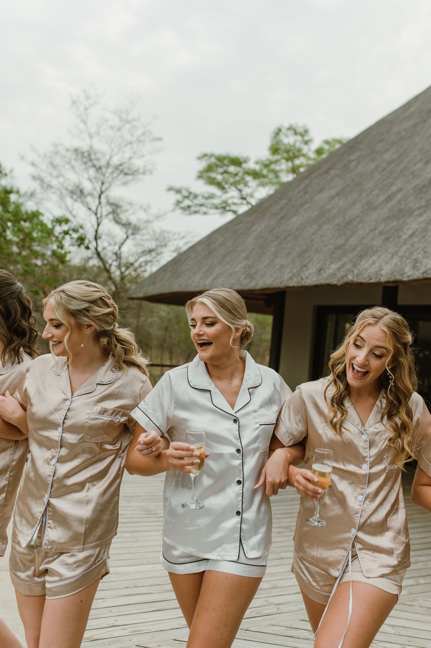 Friends in matching sleepwear share laughs while posing together on an outdoor deck.