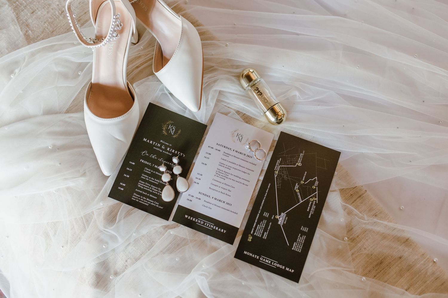 Wedding invitations and paper goods arranged on white fabric.