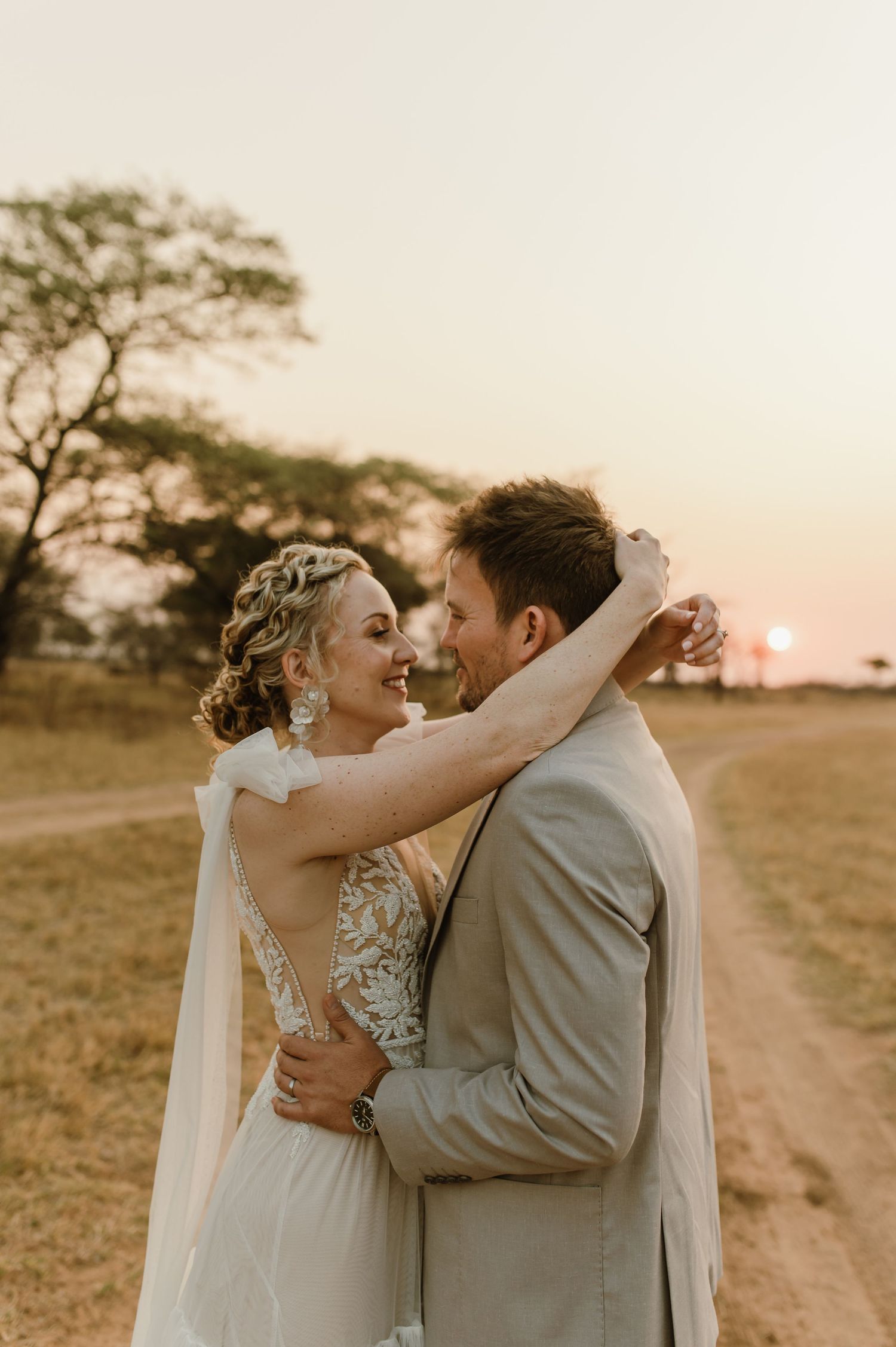 Intimate wedding portraits captured during golden hour on African savanna path.
