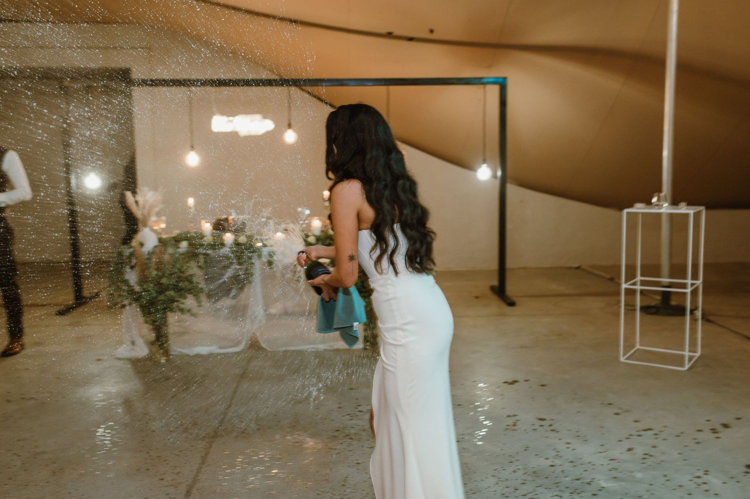 Wedding reception dance floor with guests celebrating under string lights and bubbles.
