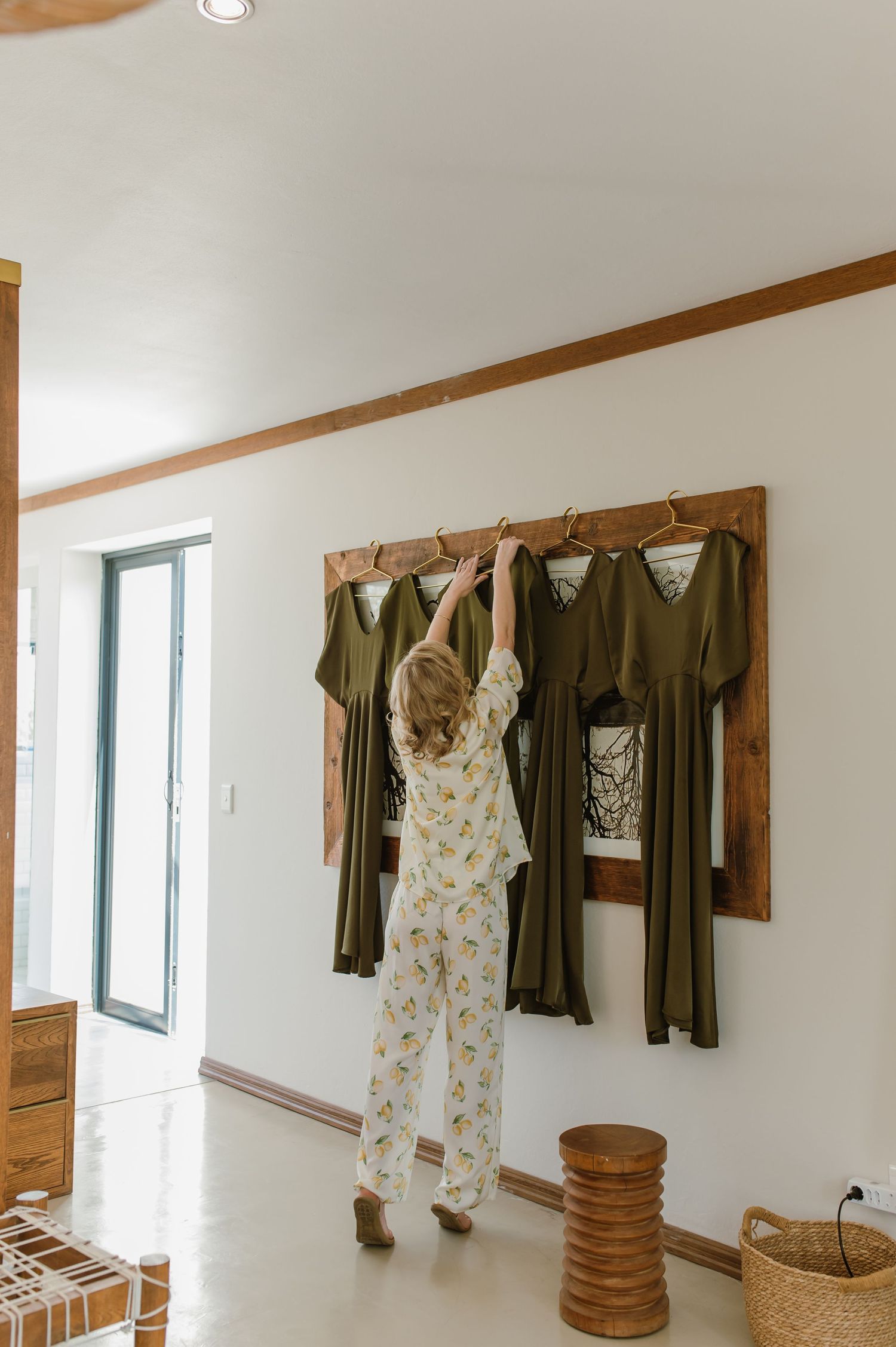 Clothing rack displaying floral and dark-colored dresses against a white wall.