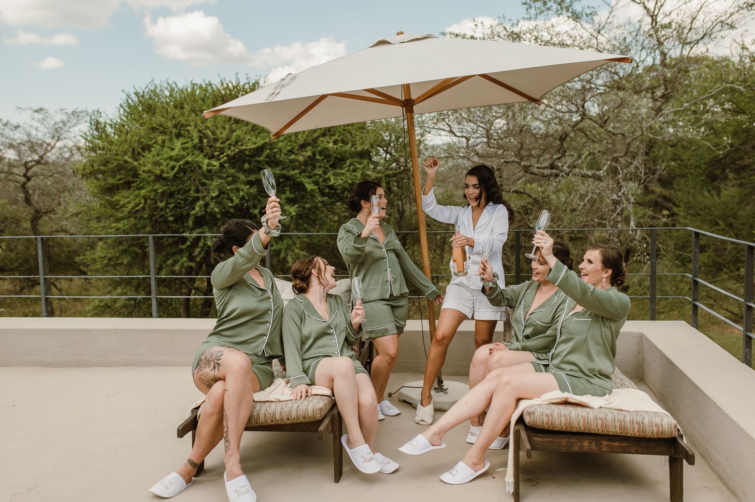 Group gathering on an outdoor terrace with umbrellas and greenery in the background.