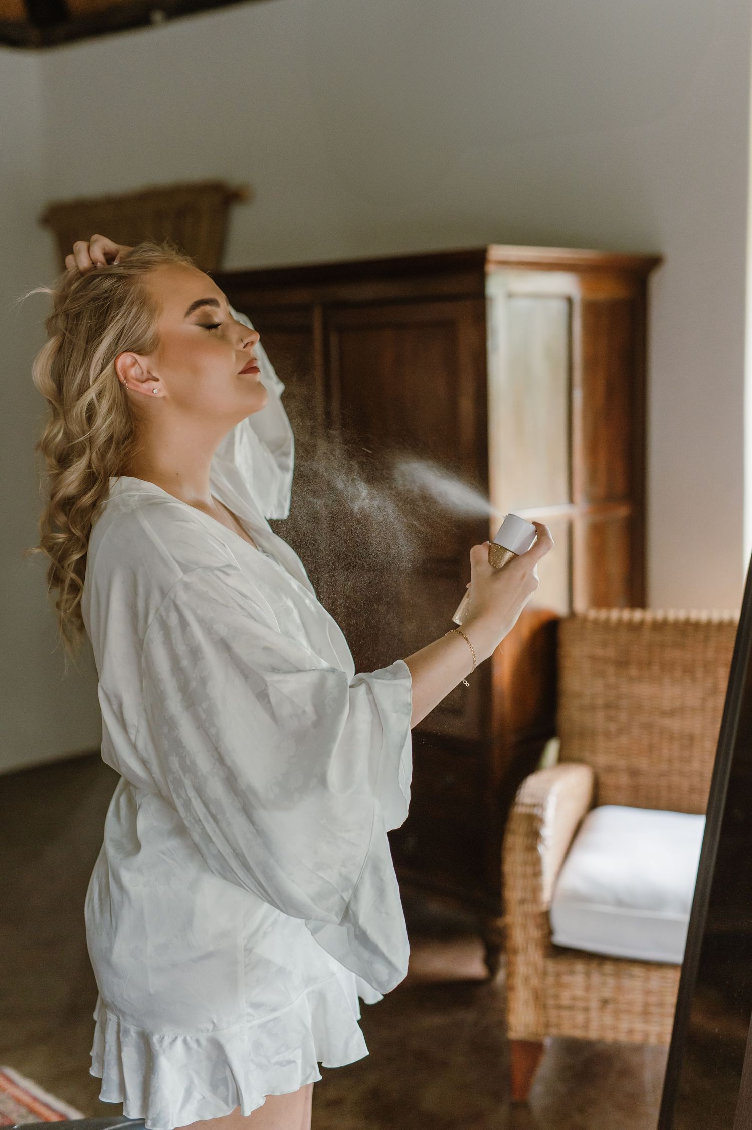 Woman in white robe getting ready in a rustic room with wooden furniture.
