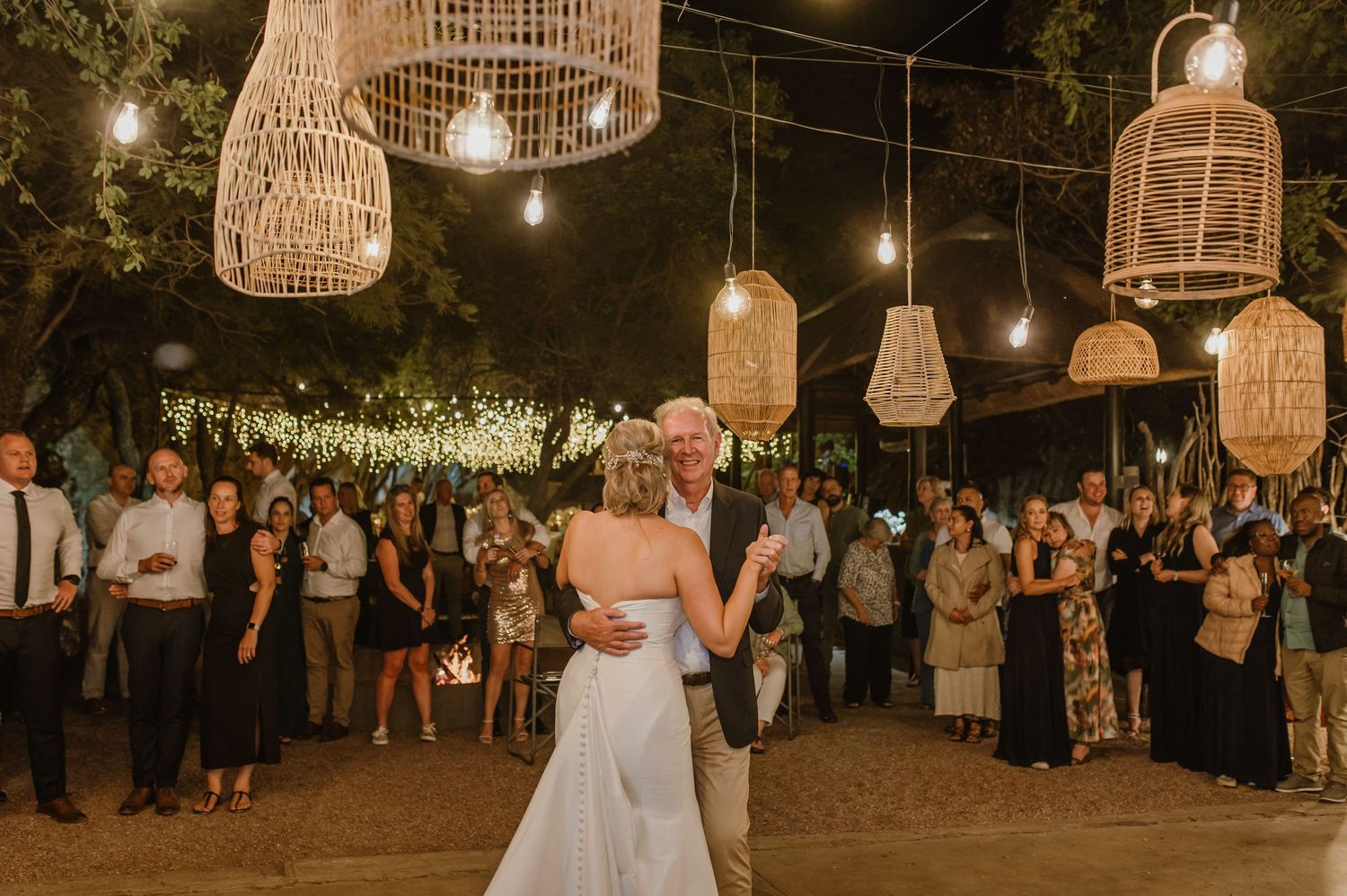 Rustic wedding venue with woven basket lanterns and string lights creating warm atmosphere.