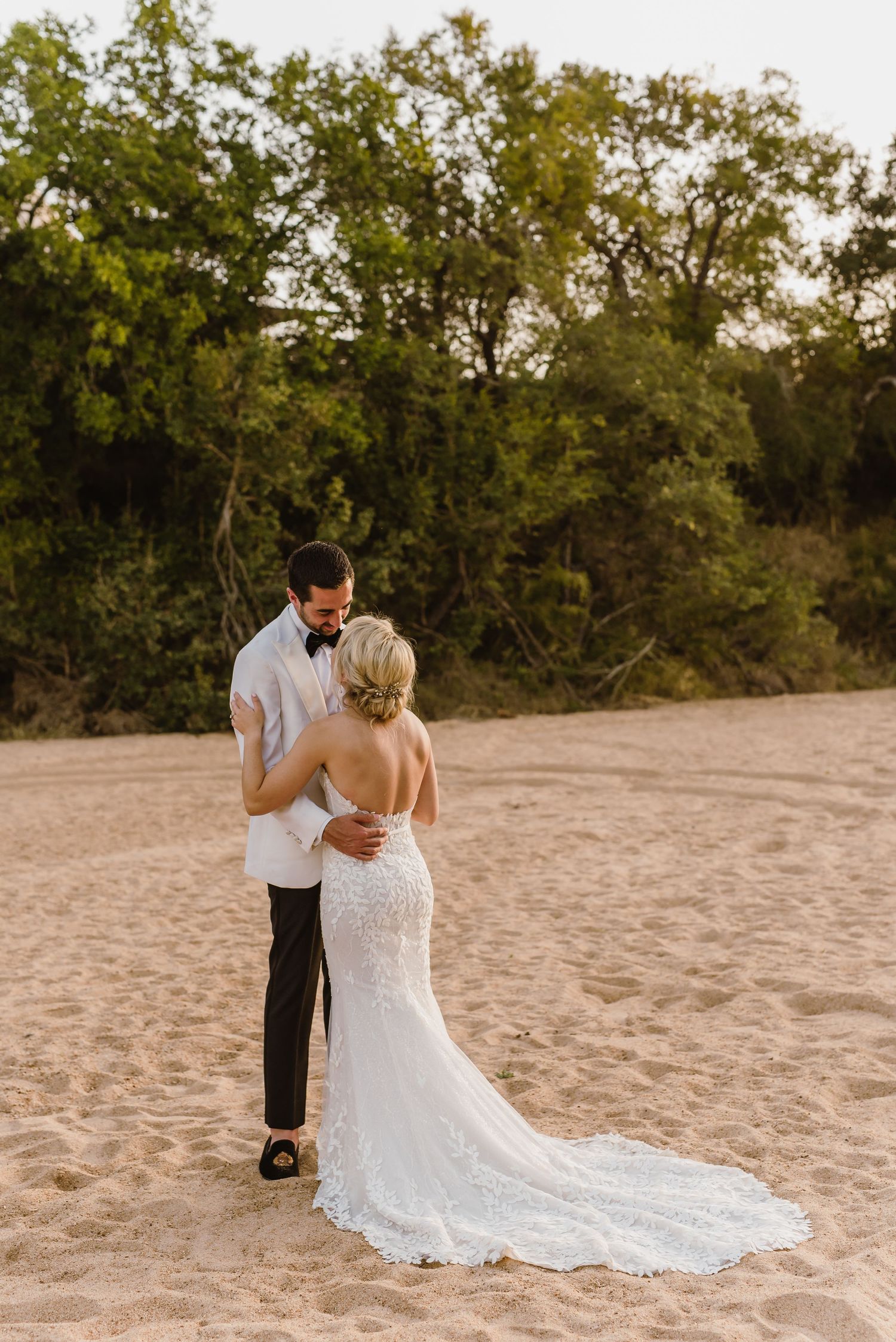 Wedding couple's silhouette against natural beach landscape at sunset.