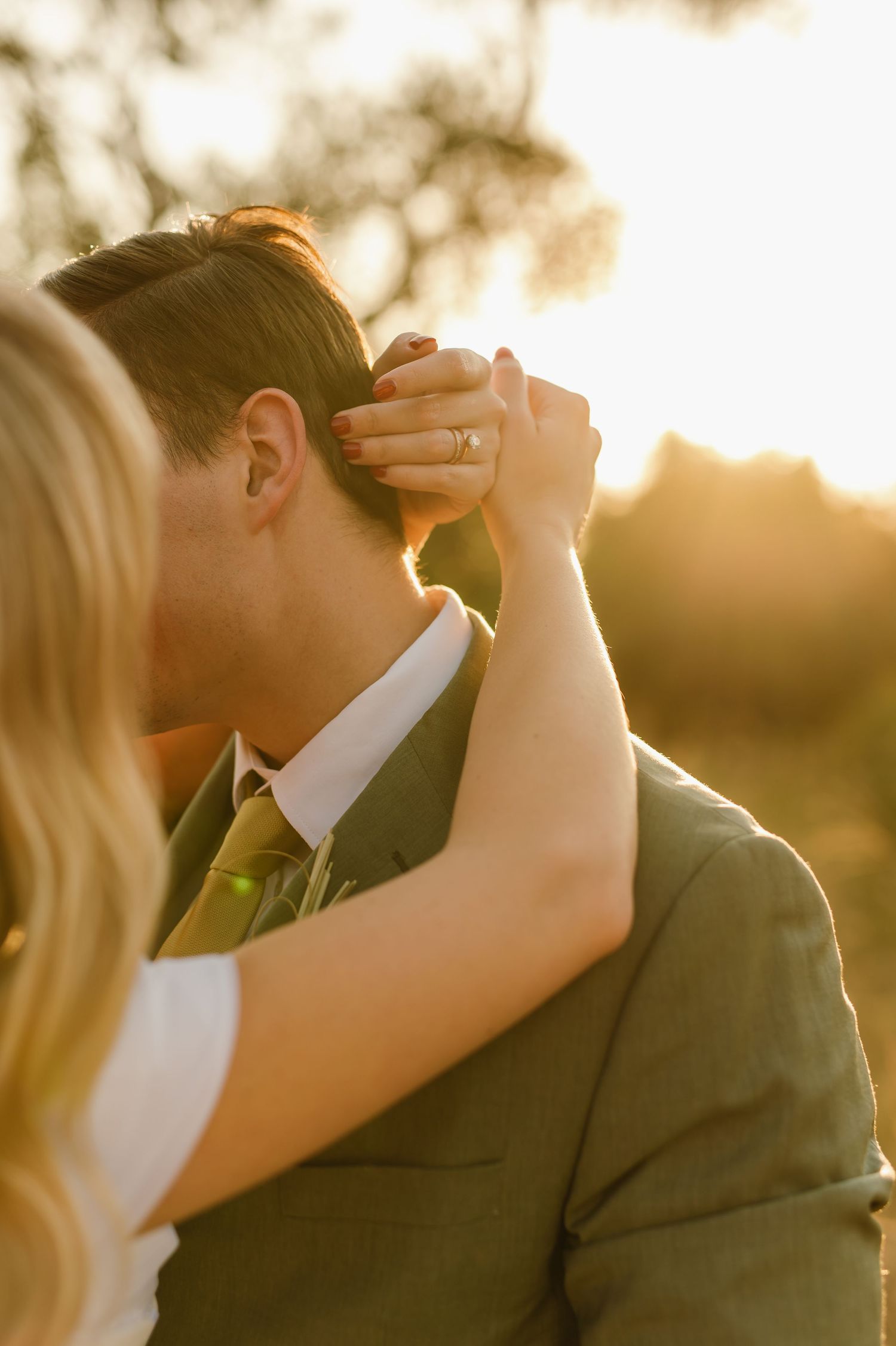Close-up wedding portrait silhouetted against warm sunset light.