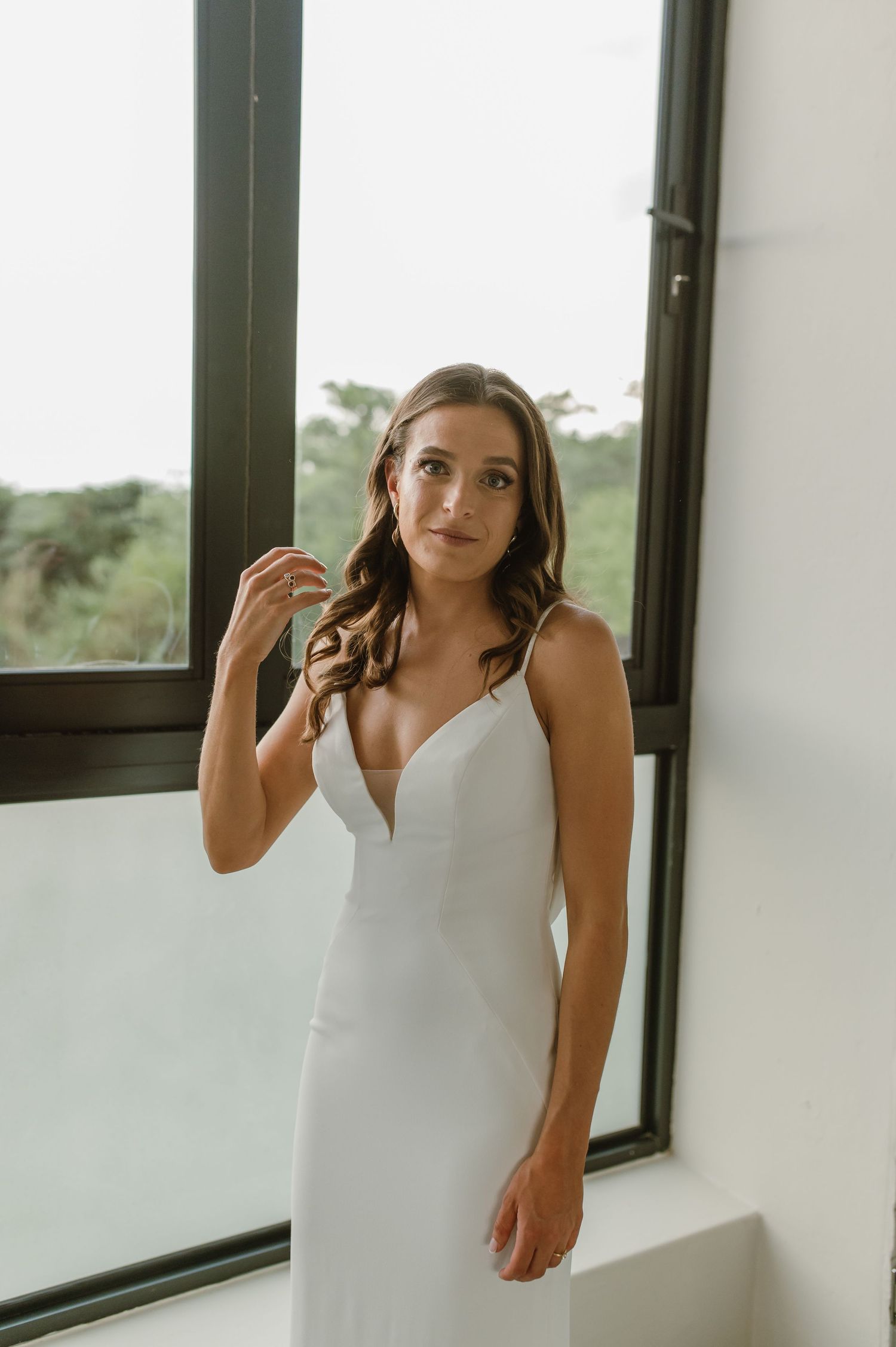 A wedding dress fitting session in a bright room with large windows.
