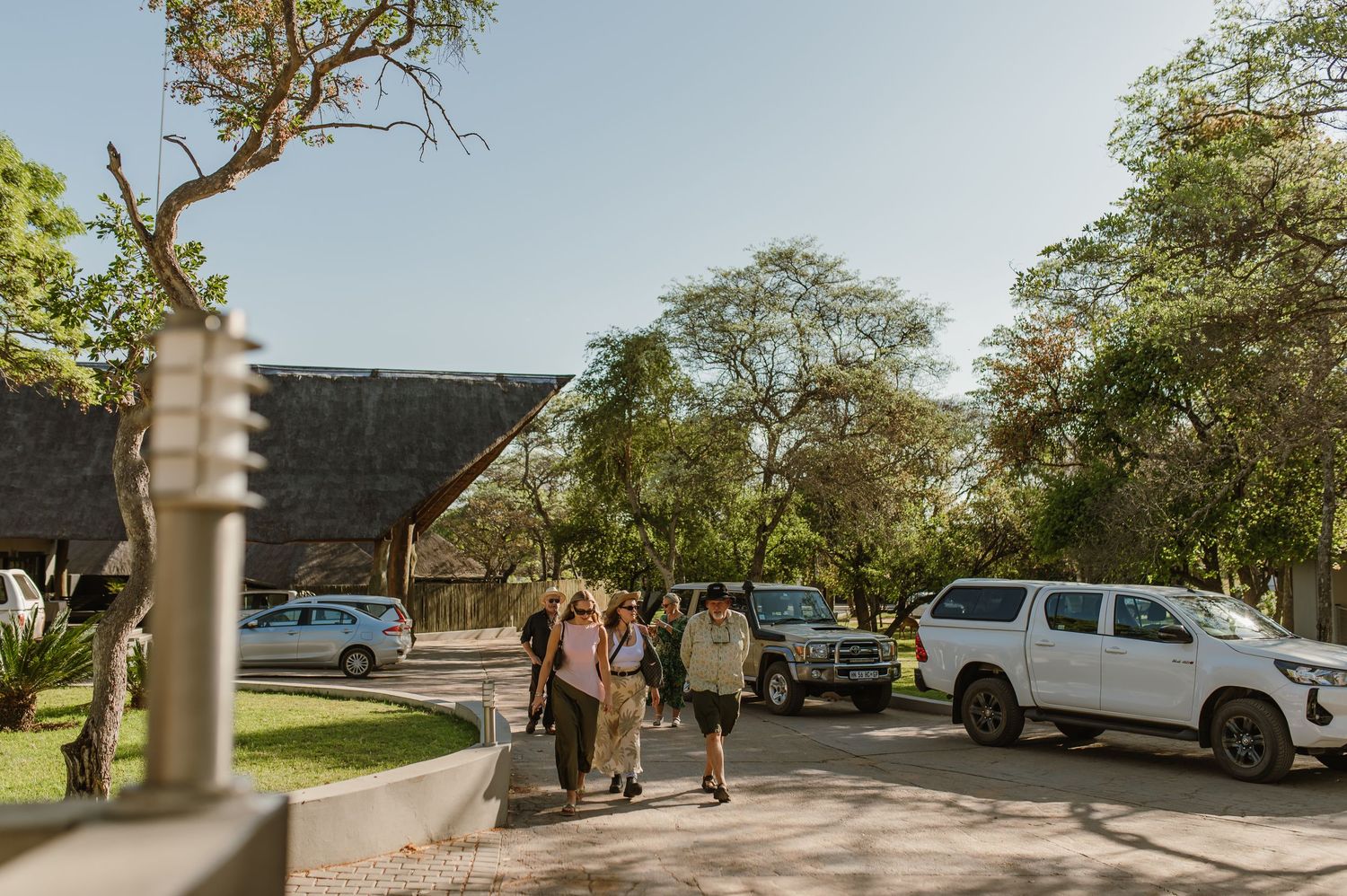 Cars parked outside a rustic venue with trees lining the driveway.