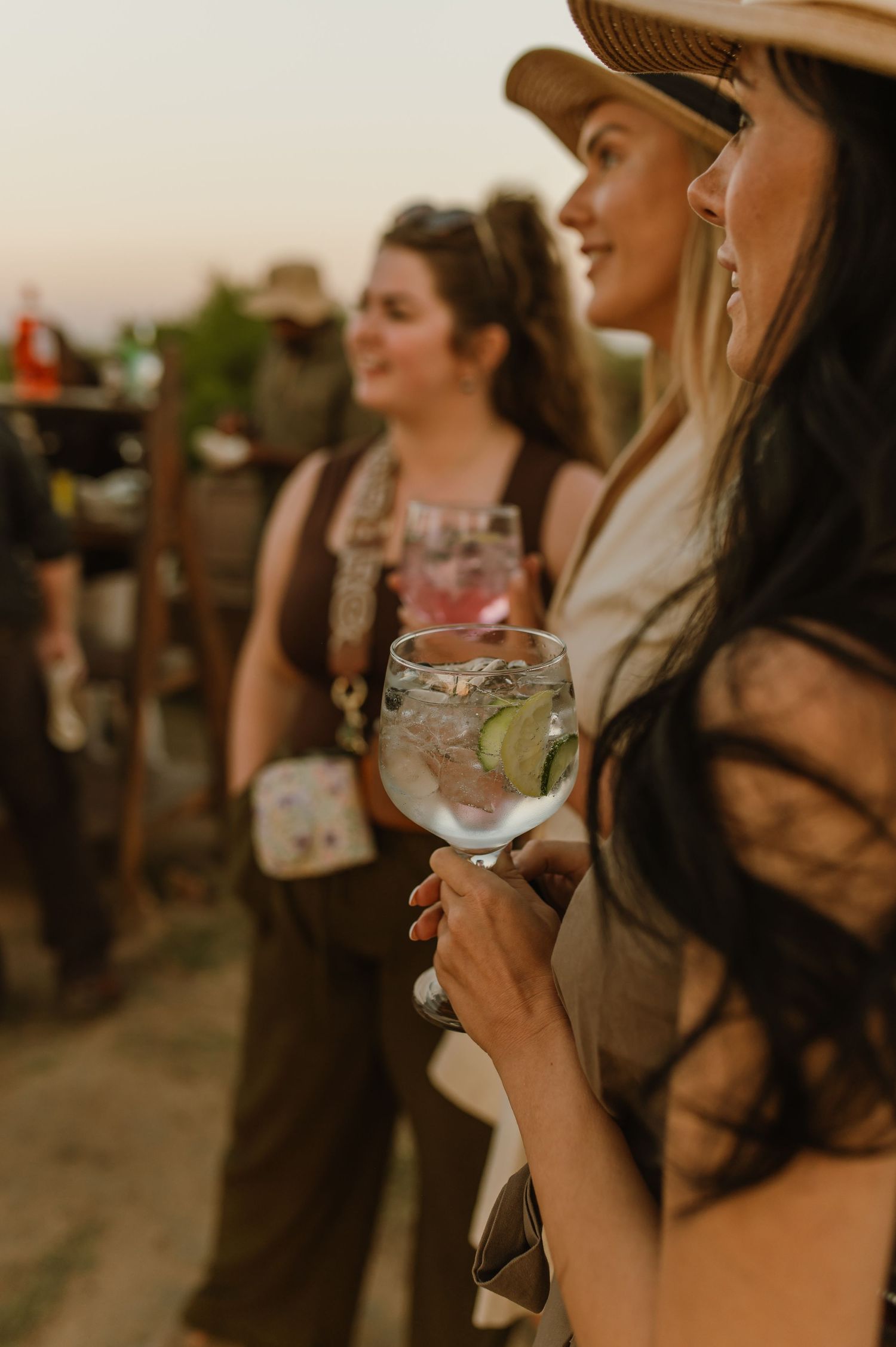 Safari guests enjoying cocktails during sunset sundowner gathering.