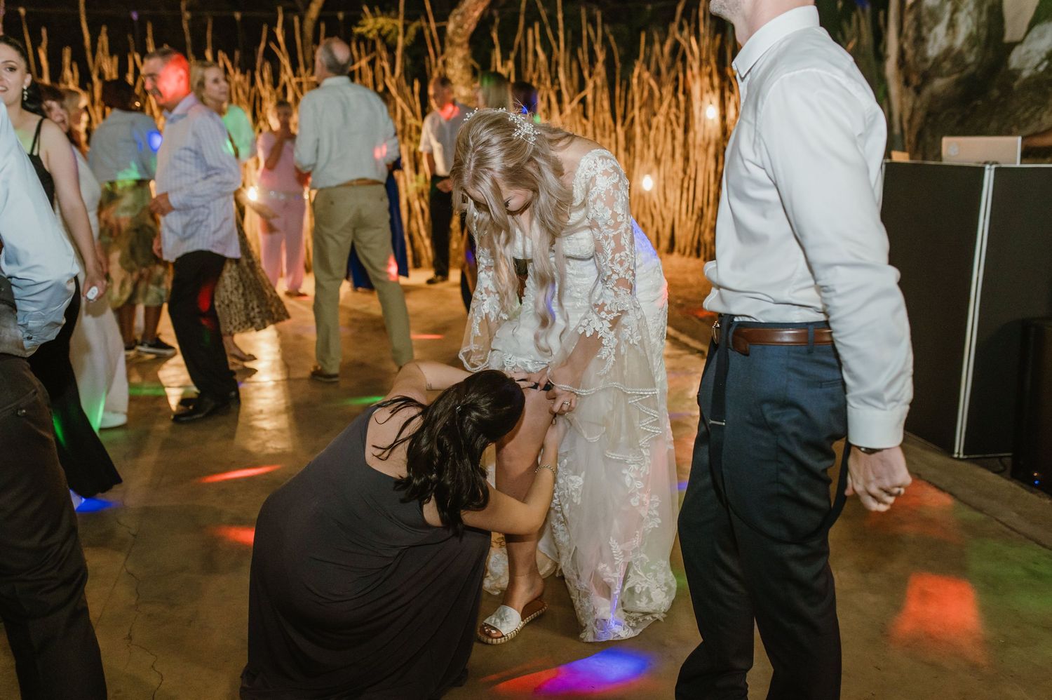 Wedding reception dance floor with guests celebrating under rustic outdoor lighting.