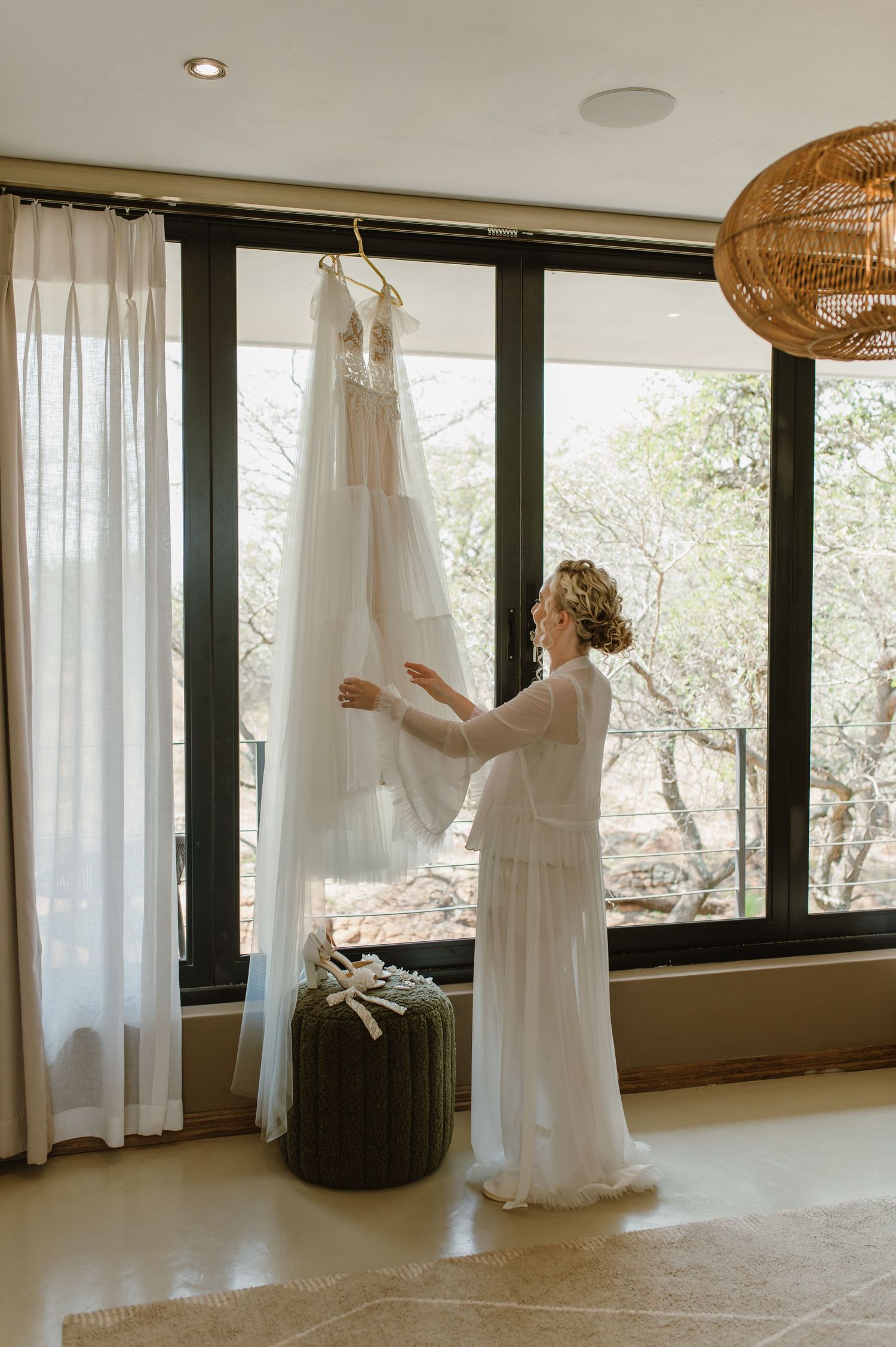 Light-filled room with white curtains and wedding dress preparations.