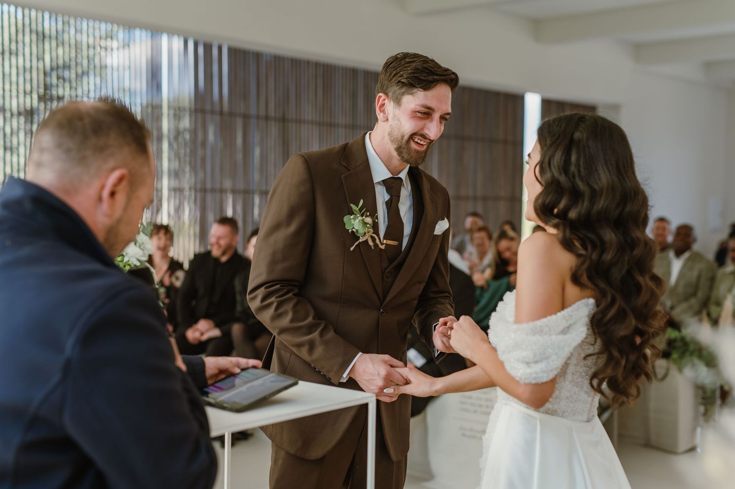 Joyful exchange between couple during wedding ceremony in bright modern venue.
