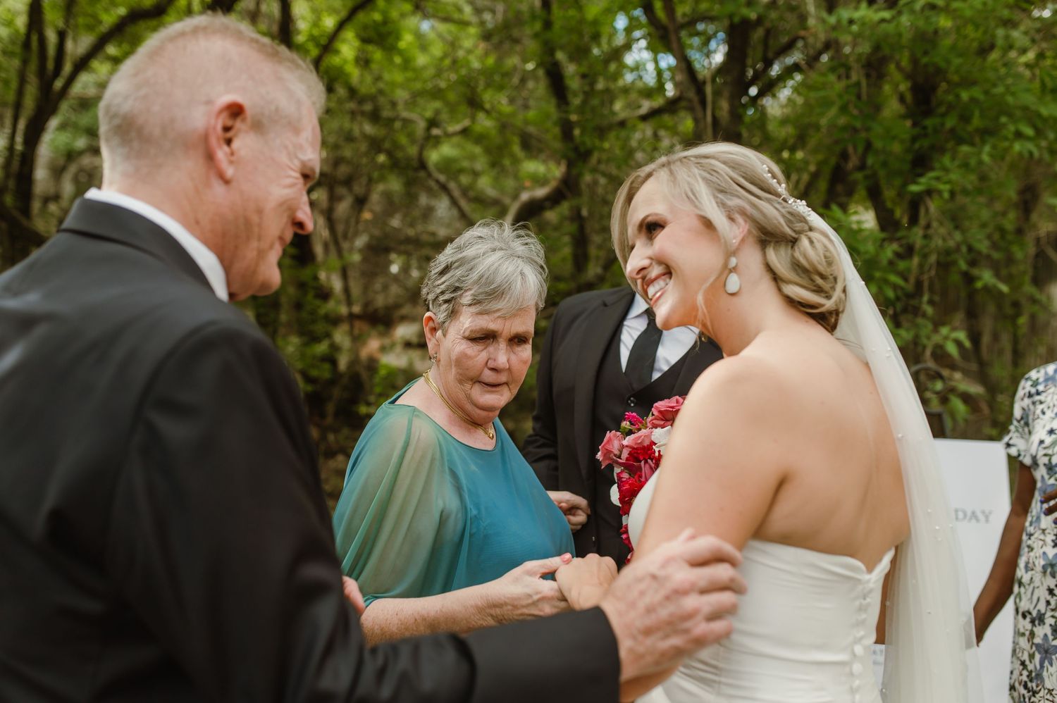 A wedding ceremony takes place outdoors as an officiant conducts the service in a natural setting.
