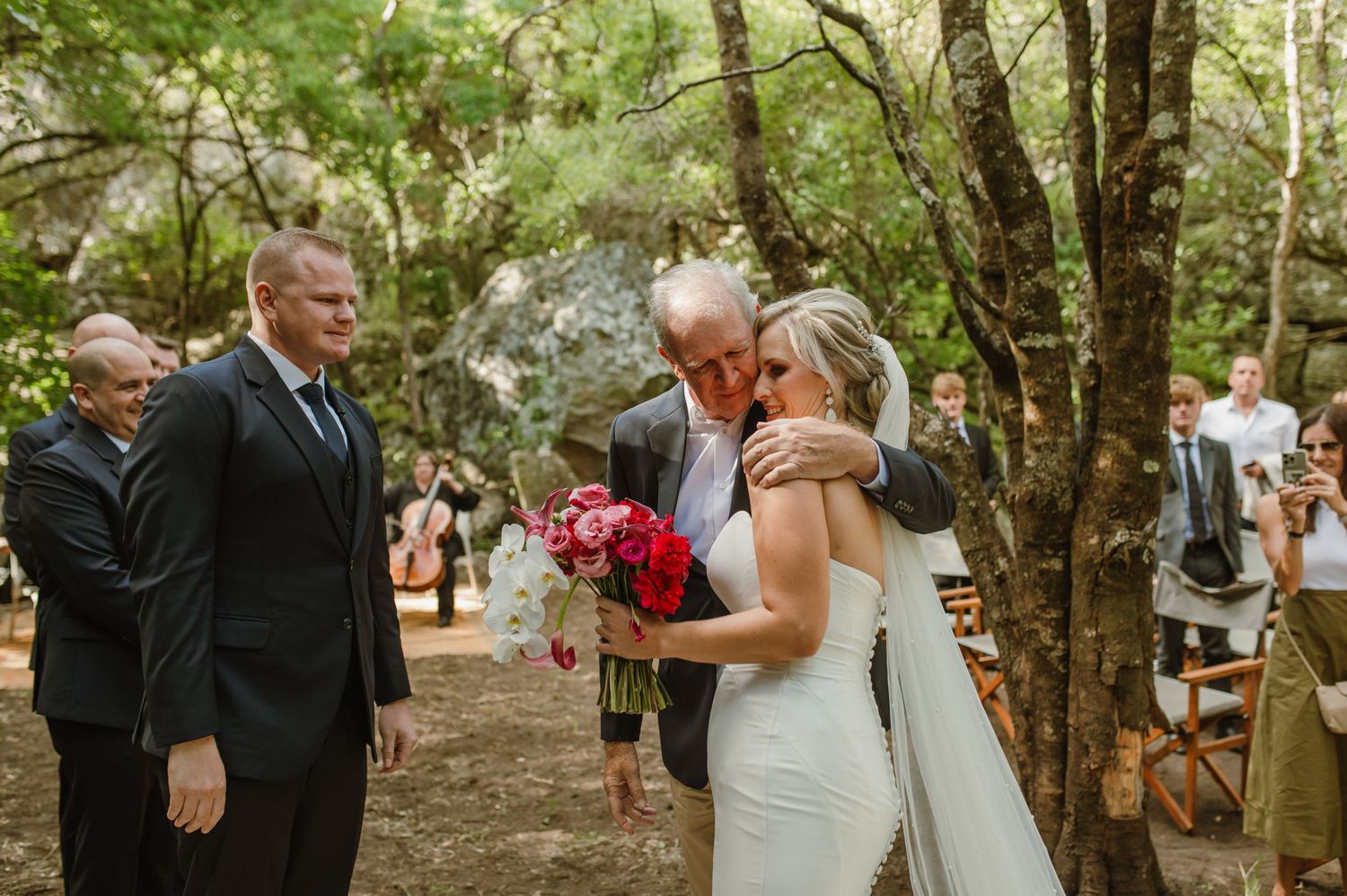 Emotional wedding ceremony moment in a sunlit forest clearing.
