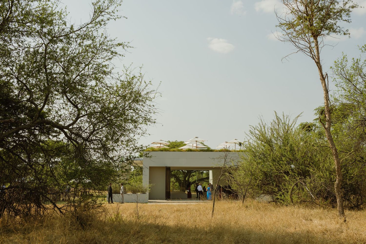 Modern minimalist building exterior with white walls and windows set against a natural landscape.