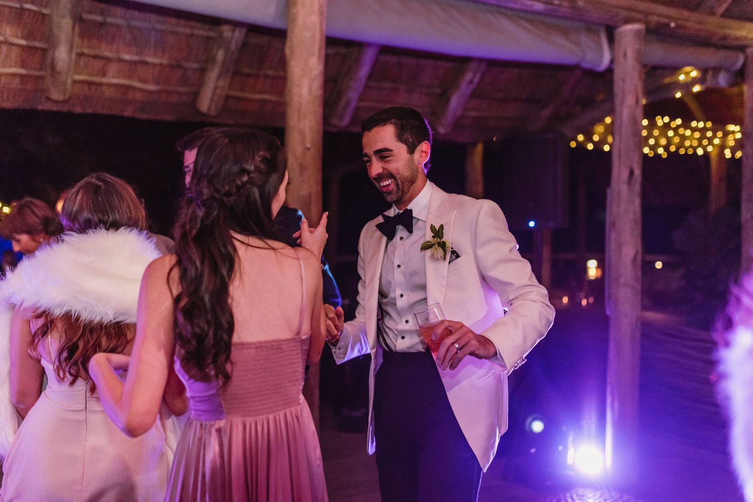 Wedding reception dance floor illuminated by purple lighting in a rustic wooden venue.