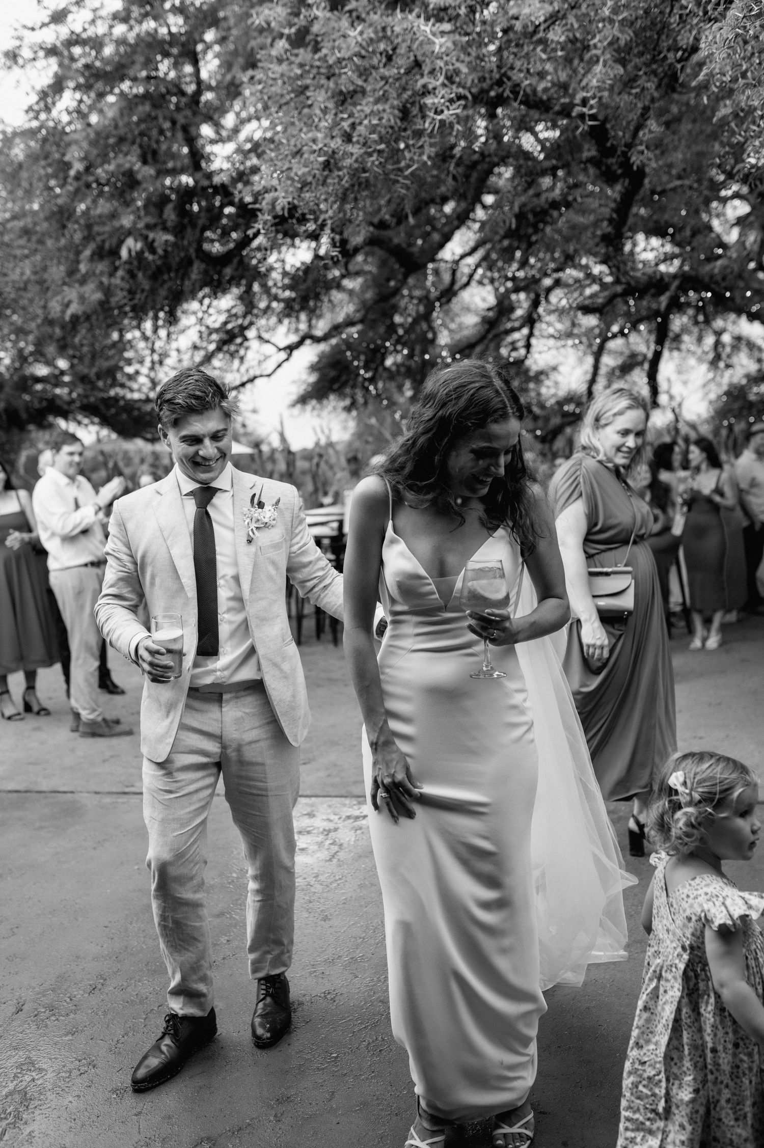Black and white photos of wedding guests walking and mingling at outdoor reception.