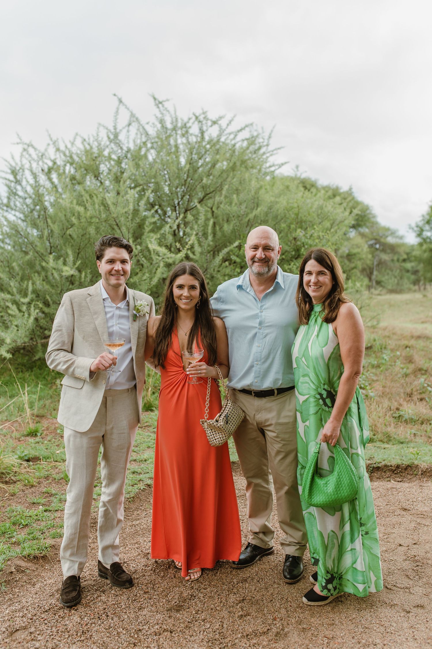 Wedding guests in formal attire posing together on a desert path with natural greenery.