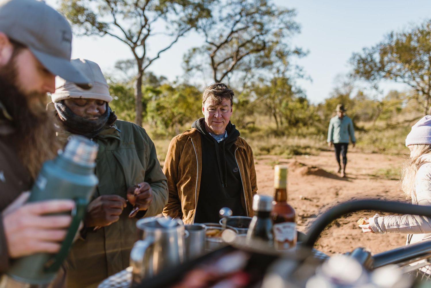 A group of people enjoying drinks and conversation at an outdoor gathering in a desert landscape setting.