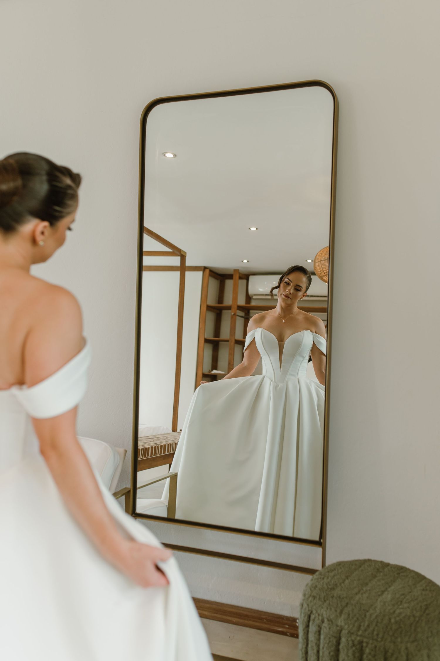 Reflection of wedding dress being fitted in full-length gold framed mirror.