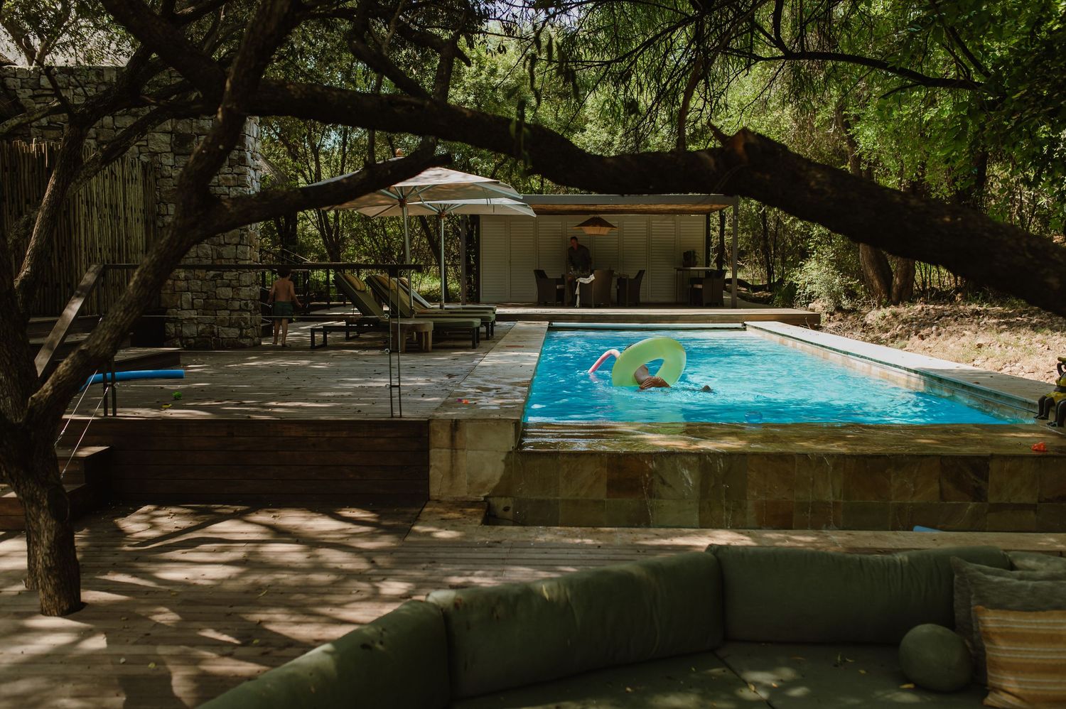 Serene outdoor pool surrounded by trees and wooden deck at a Relais & Chateaux safari lodge.