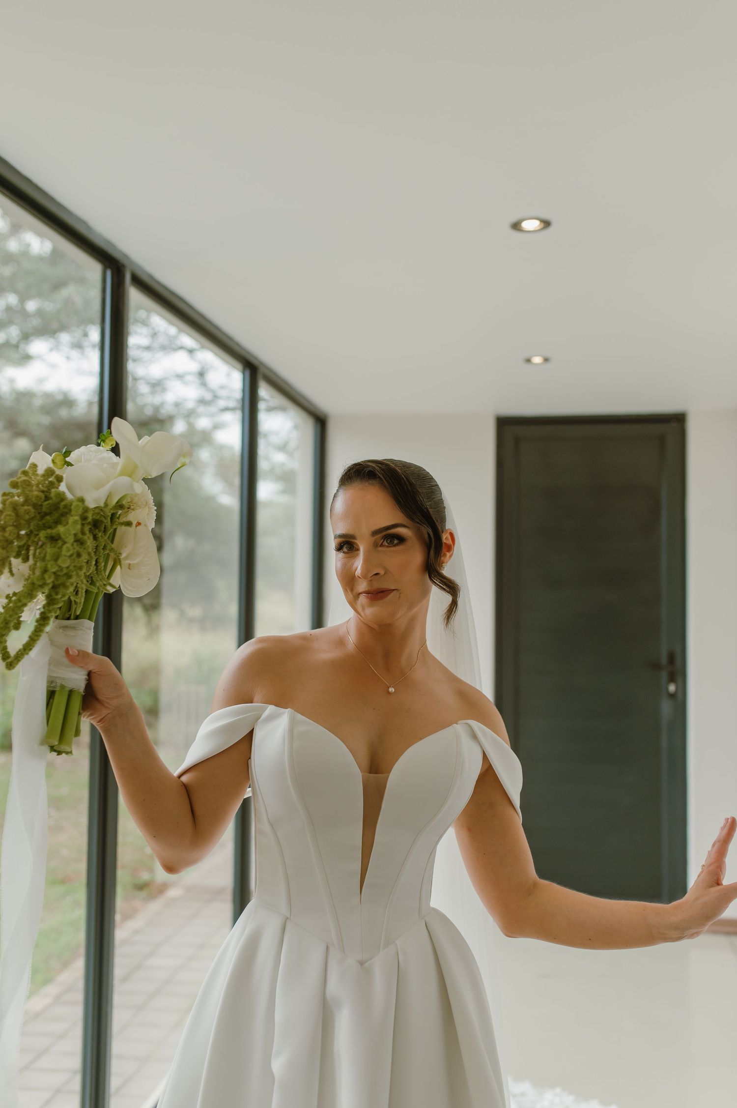 A bride in an elegant white wedding gown with a plunging neckline holds white flowers.