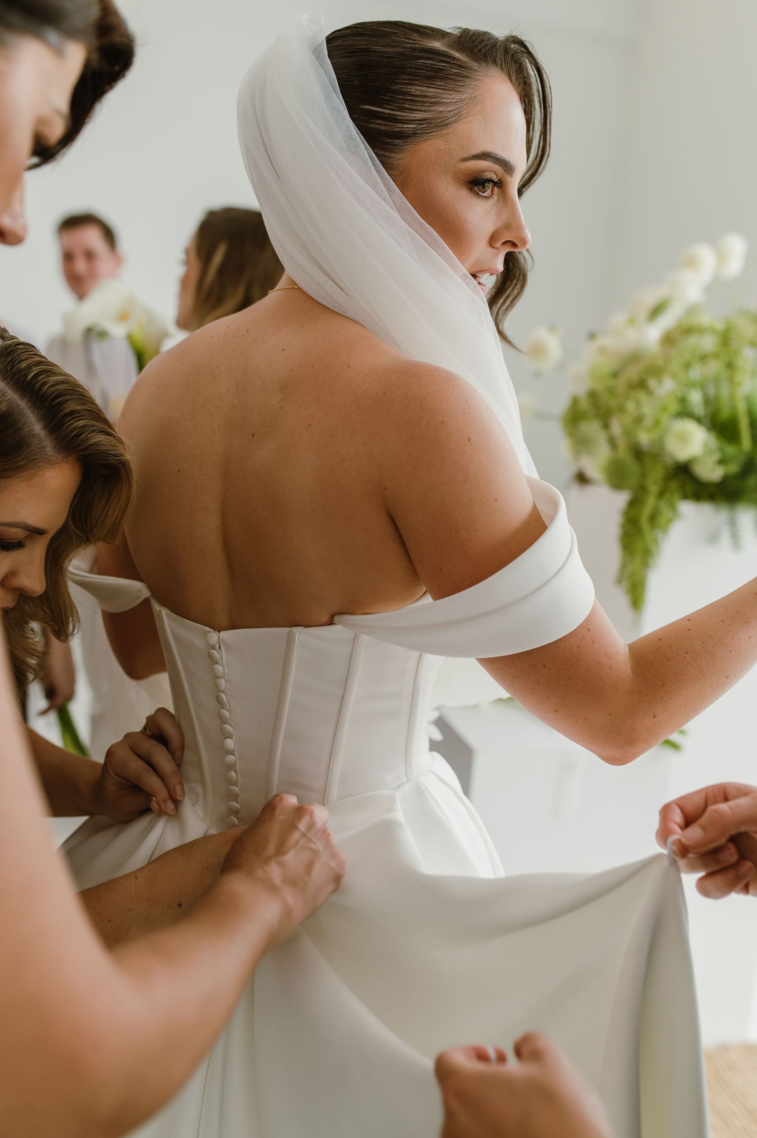 Close-up details of a white wedding dress with off-shoulder design and button closures.