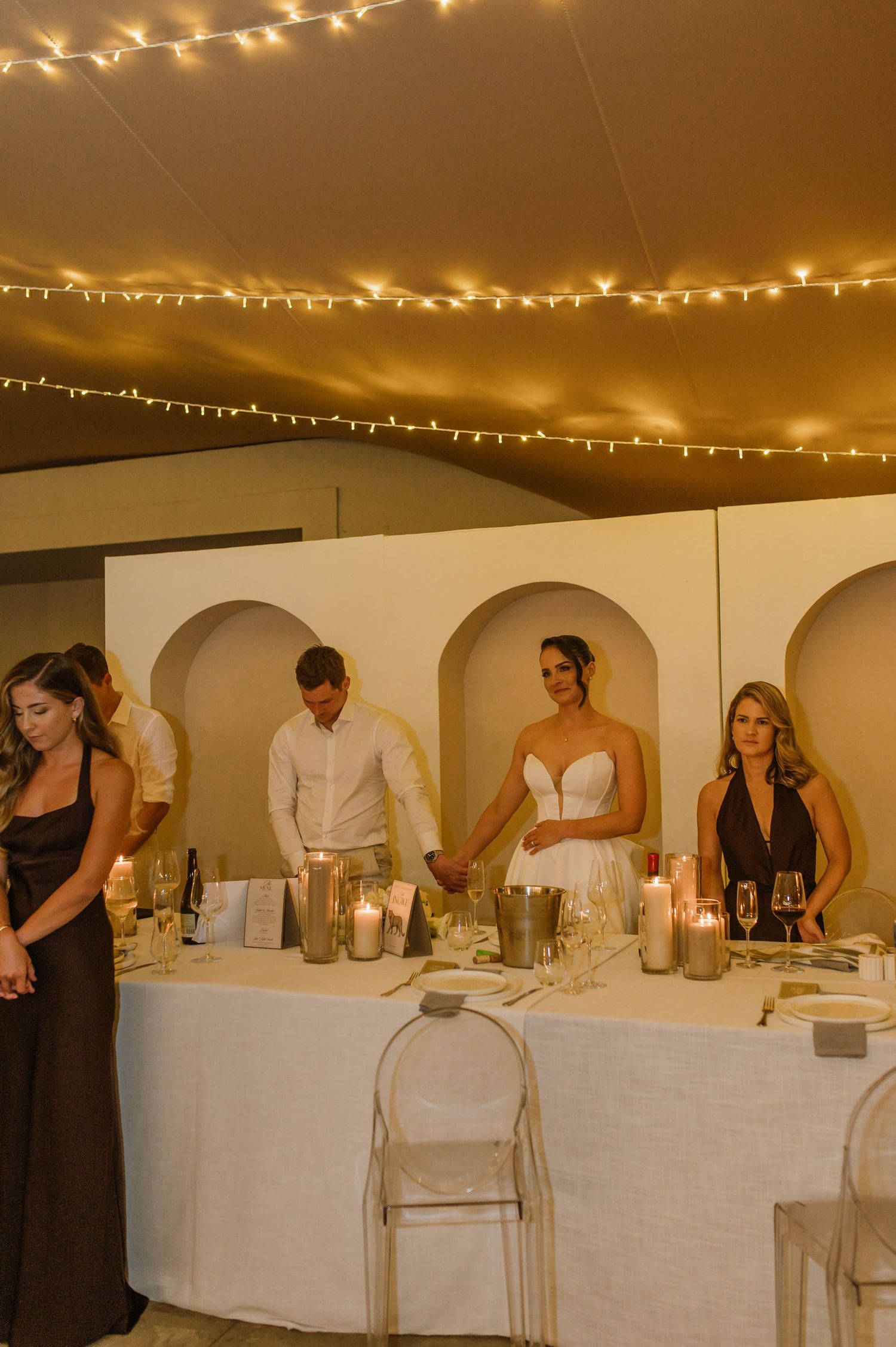 Wedding reception setup with white tablecloths and string lights creating an elegant ambiance.
