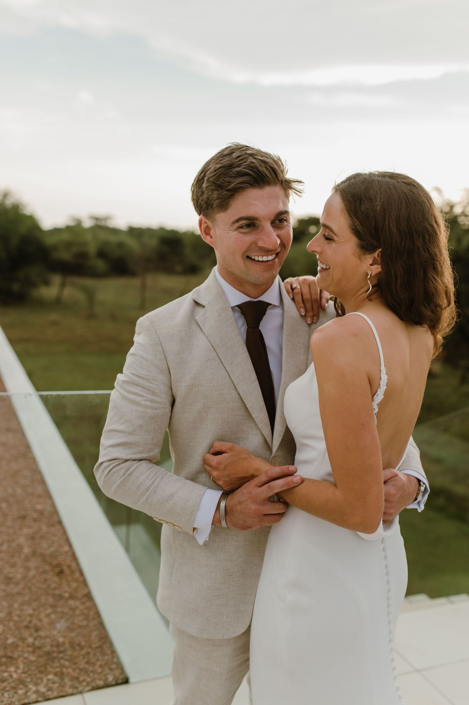 Happy newlyweds share a lighthearted moment on a modern terrace.