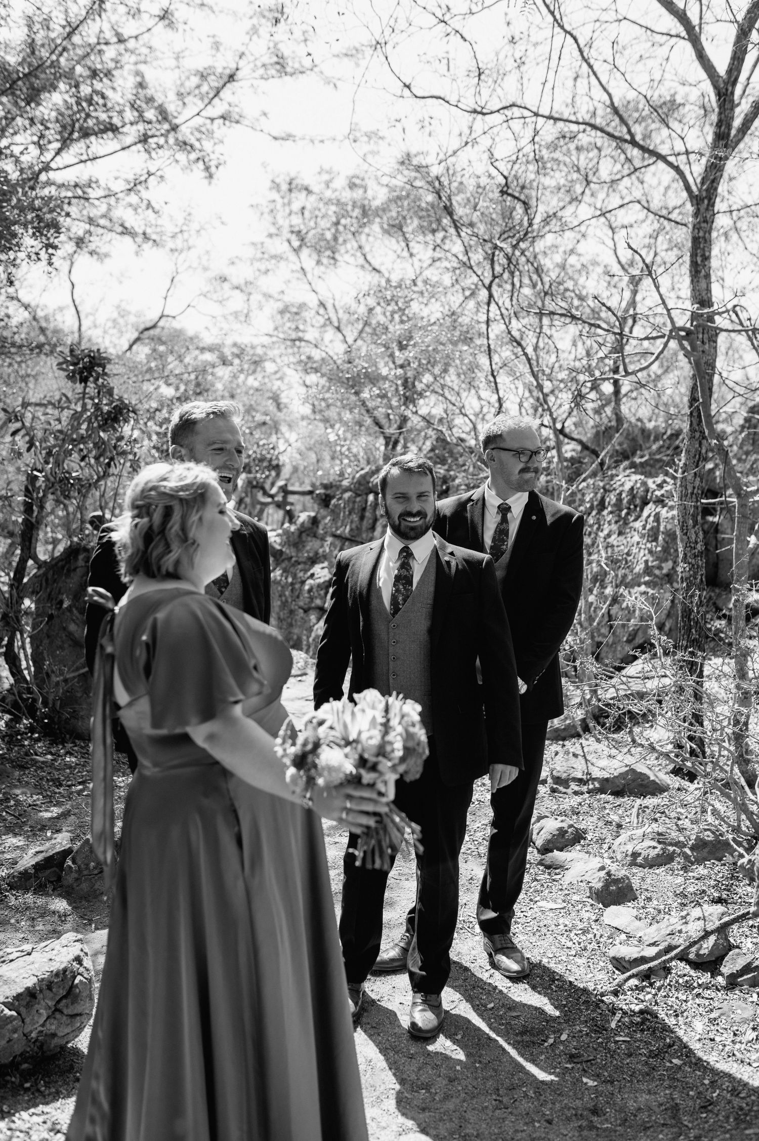 A black and white wedding ceremony moment captured in a natural wooded setting.
