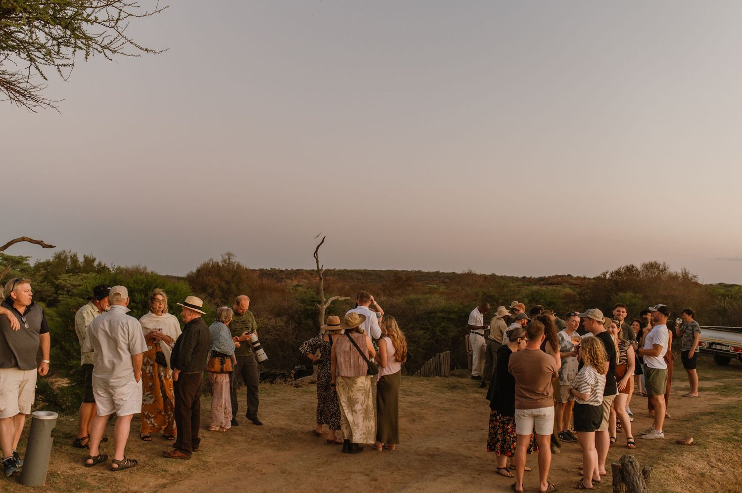 Scenic outdoor event with people gathered on a hillside at dusk.