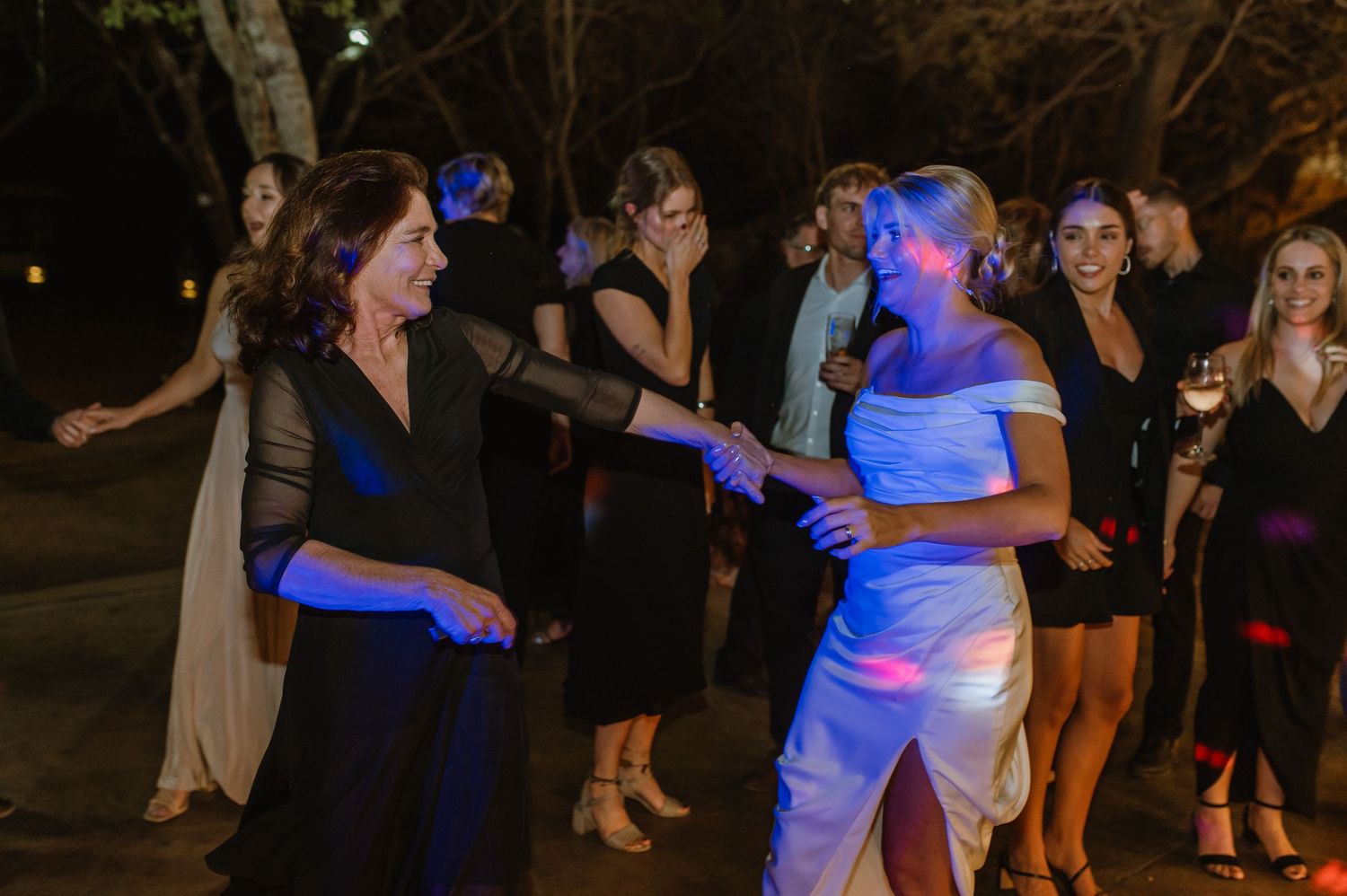 Guests enjoying a lively dance party at an outdoor evening wedding celebration.