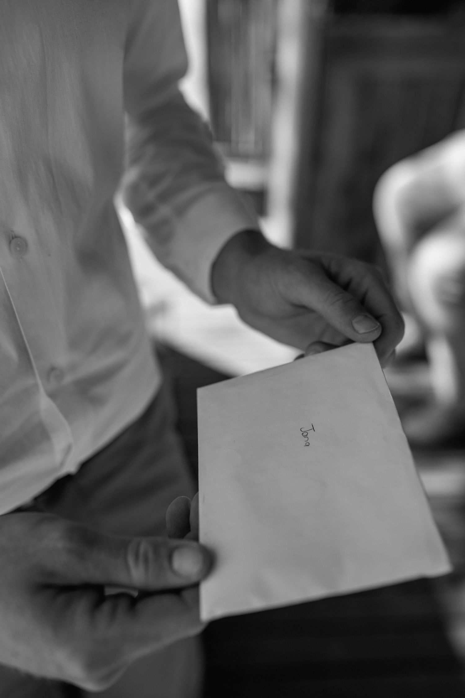 Hands holding a white envelope in black and white photography.