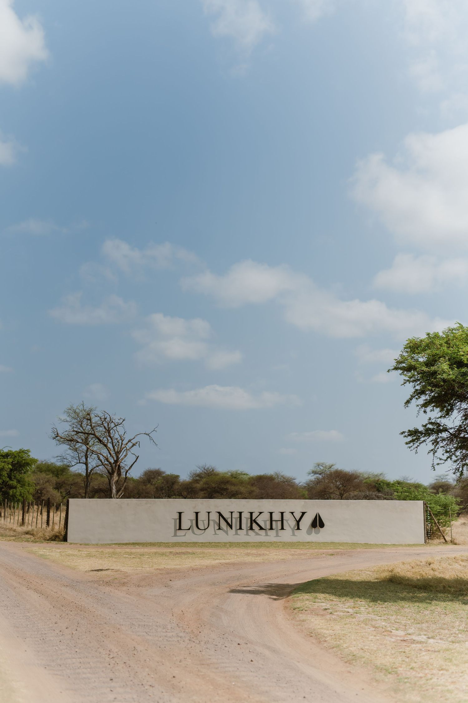 Outdoor venue with swimming pool and lounge areas surrounded by acacia trees.