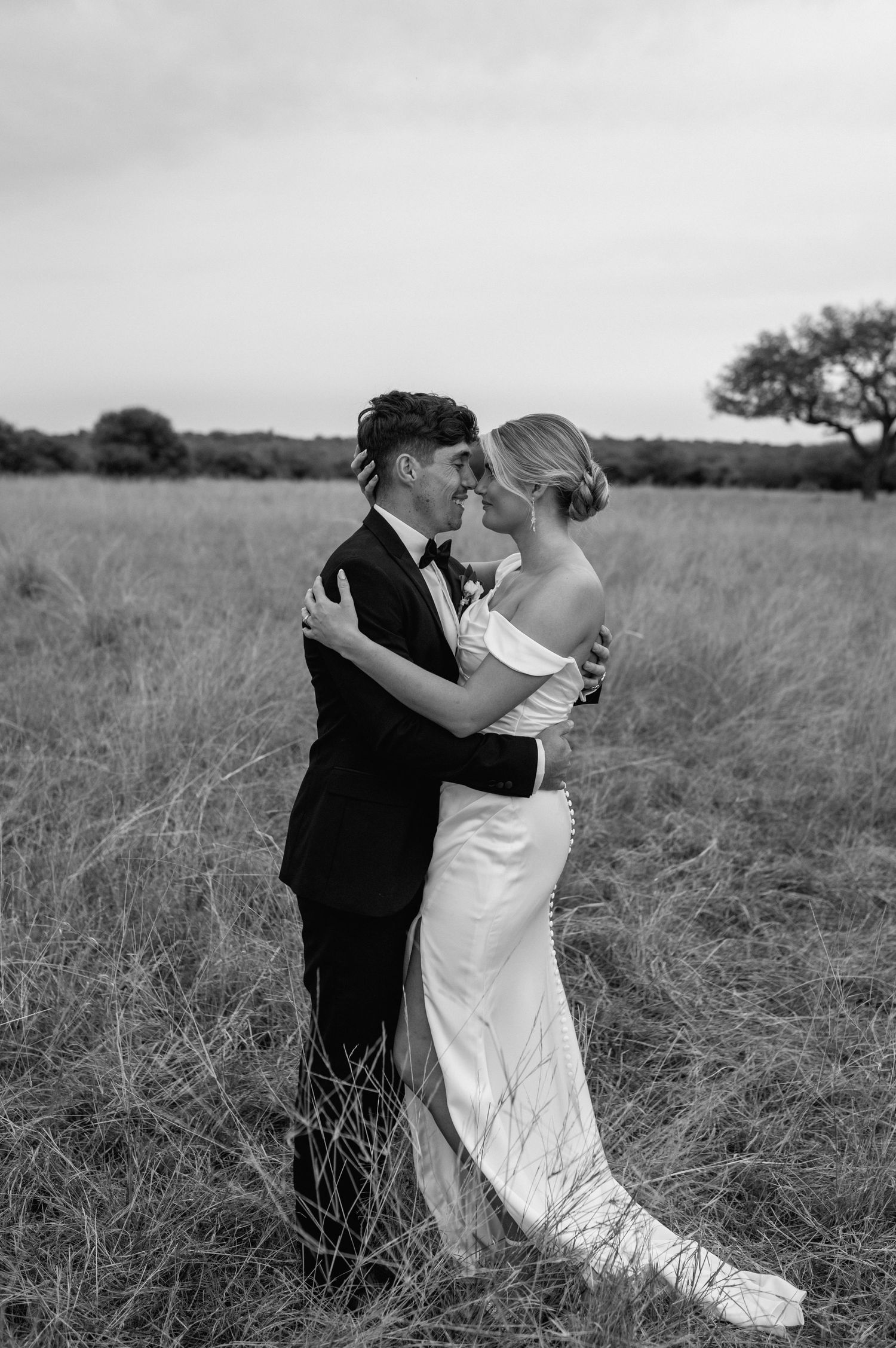 Black and white wedding photos capture intimate moments between a couple in a rural field.