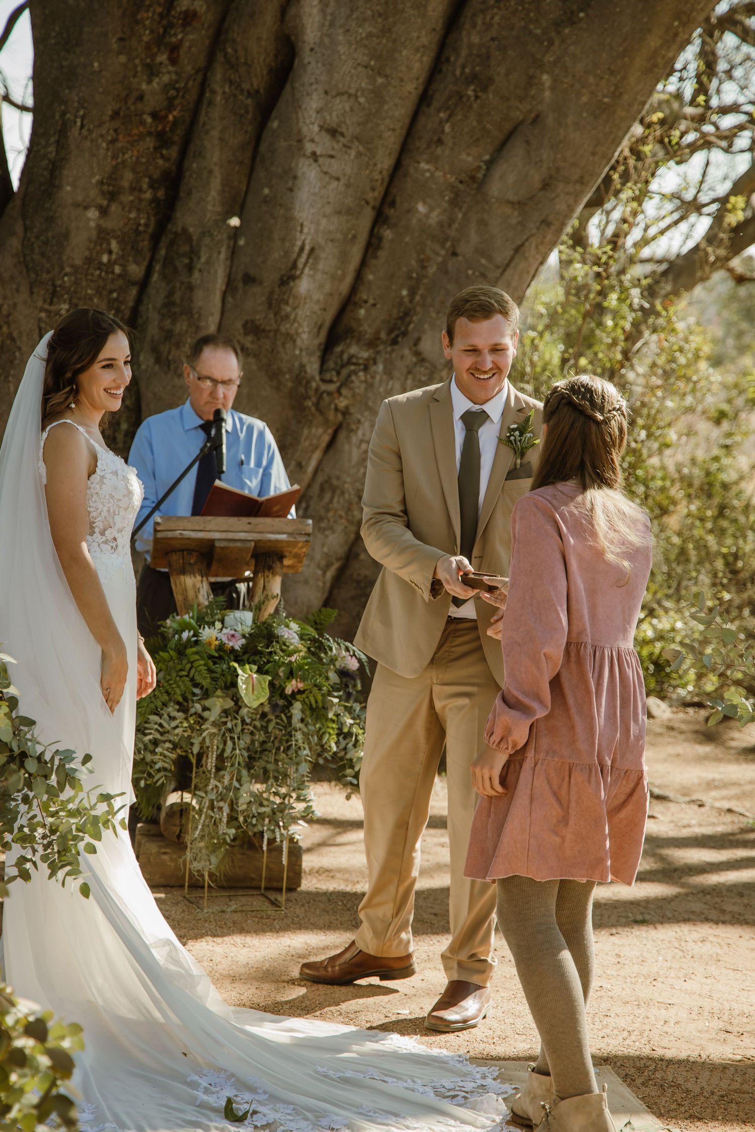 Intimate wedding ceremony moments captured under a majestic desert tree.